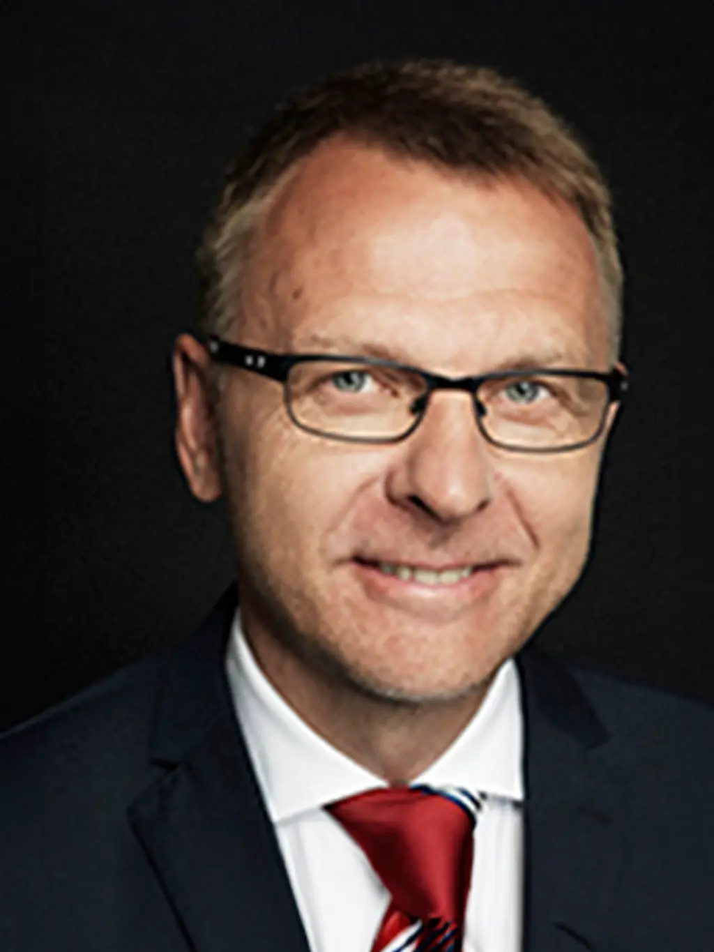 Mies katsoo kameraan hymyillen