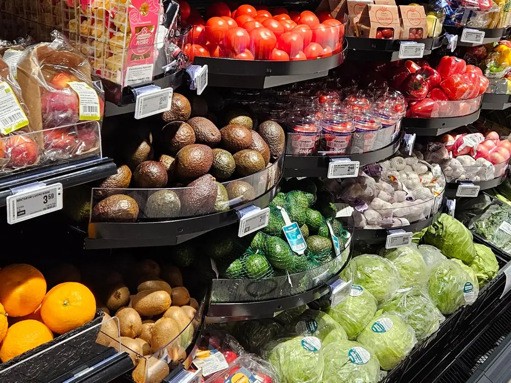 Kuva kaupan hedelmä- ja vihannesosastosta, avokadoja, appelsiineja, salaattikeriä, ja tomaatteja
