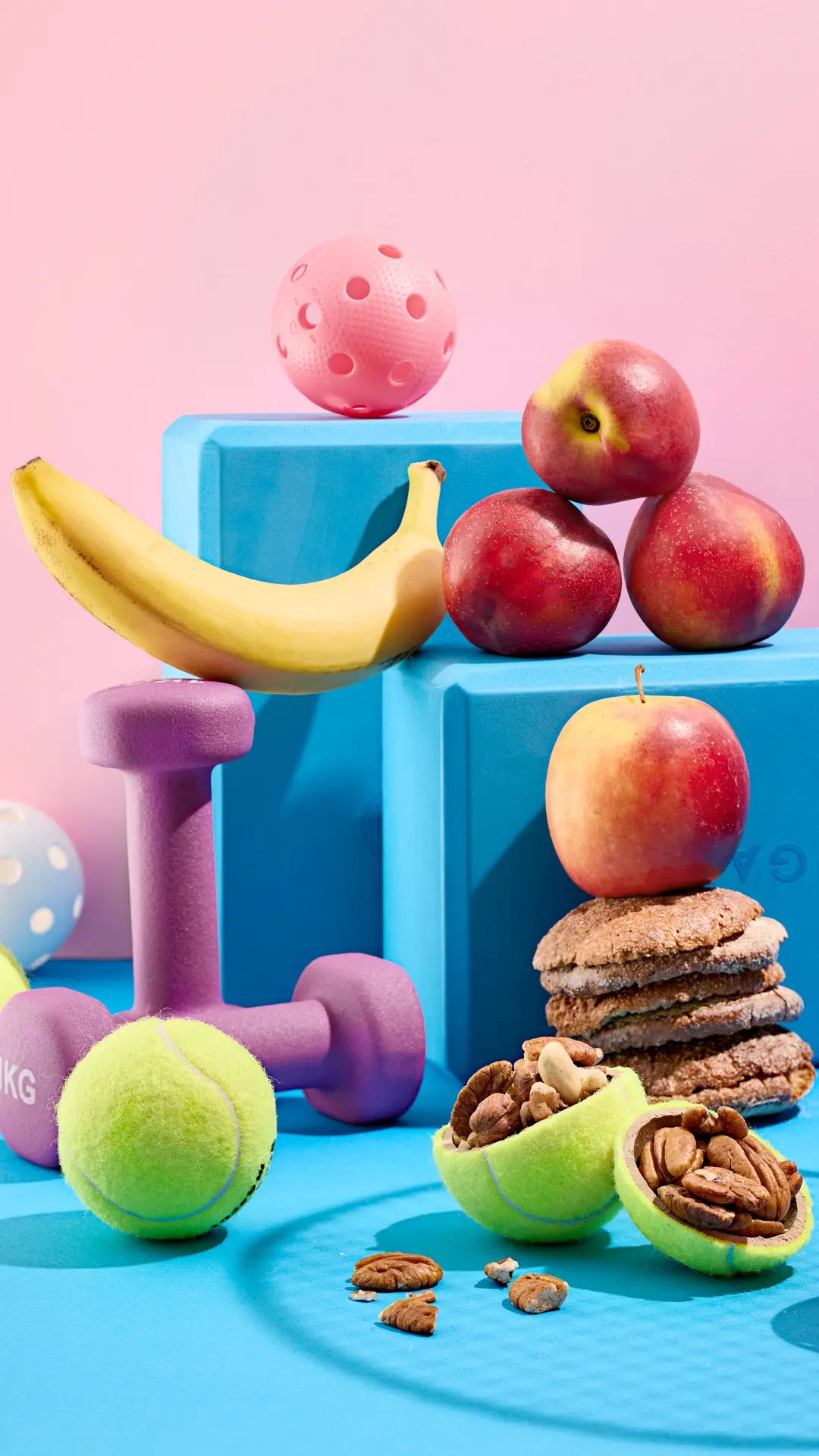 Käsipainoja, banaani ja omenoita. Tennispallon puolikkaat on täytetty pähkinöillä.