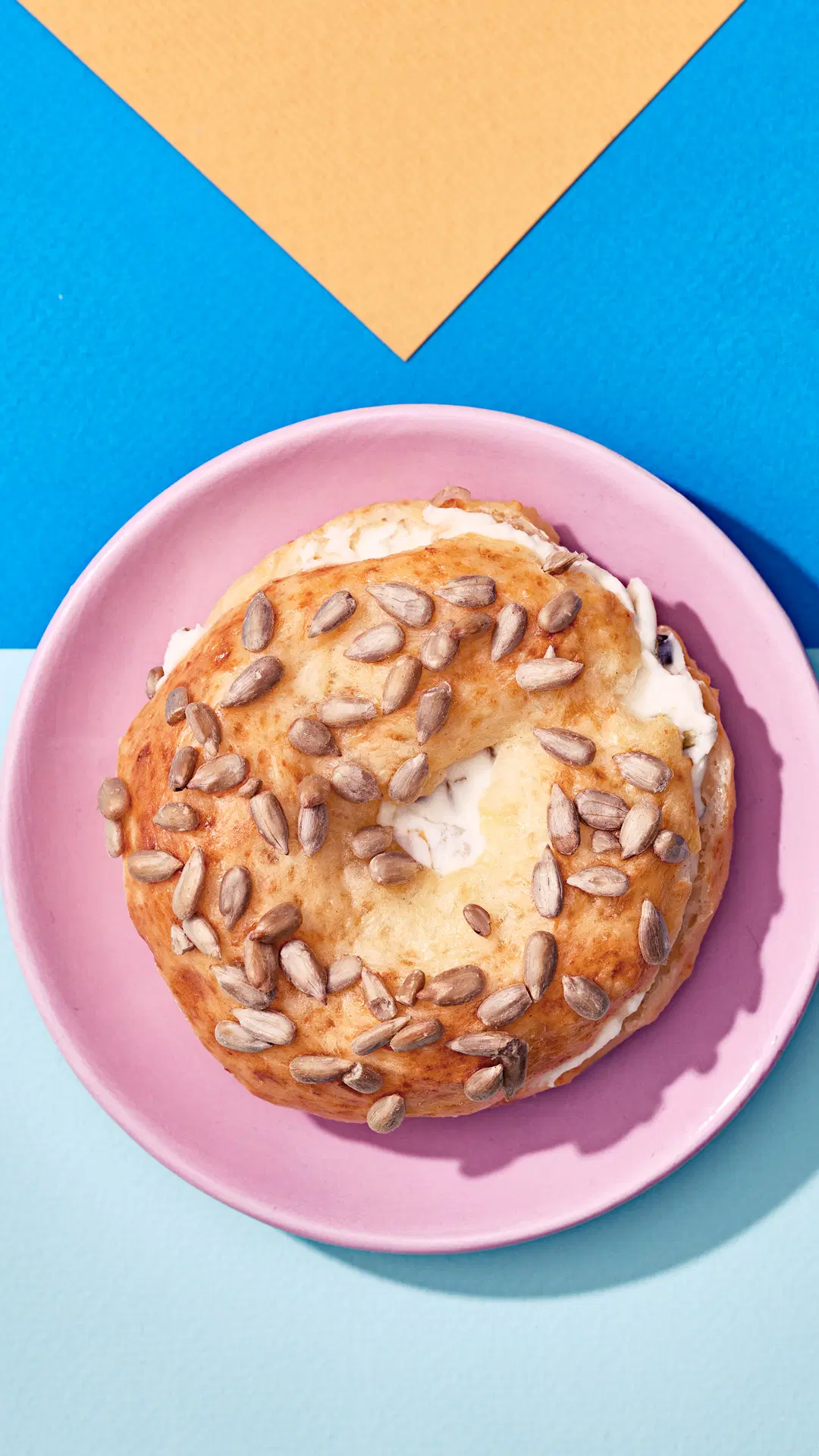 Bagel, jonka päällä auringonkukansiemeniä ja välissä tuorejuustoa.