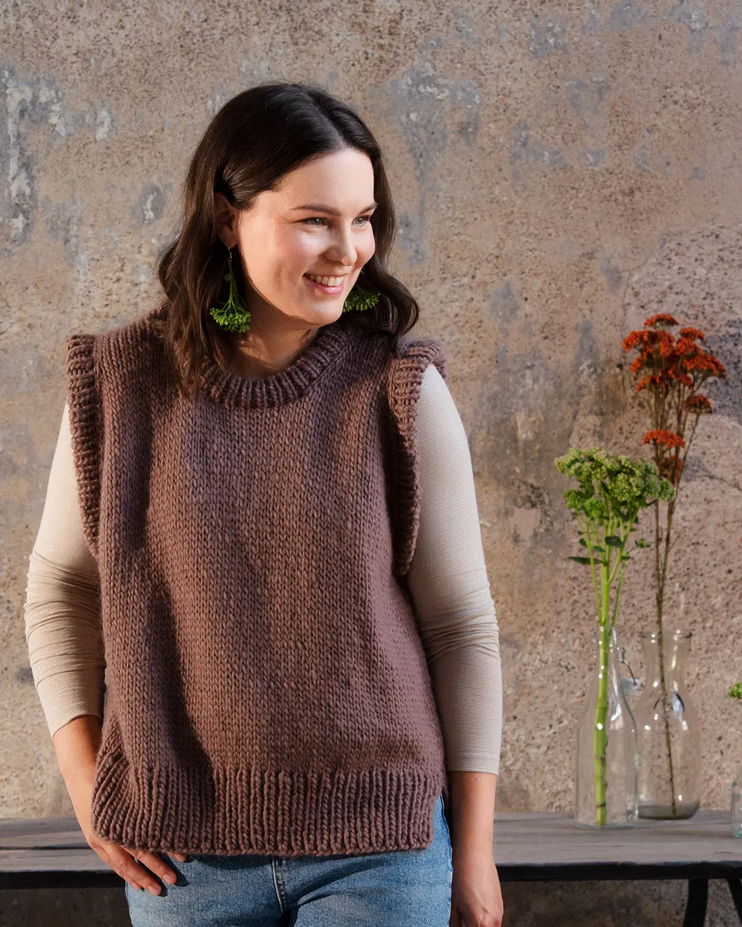 Nainen, joka on pukeutunut ruskeaan neuleliiviin.