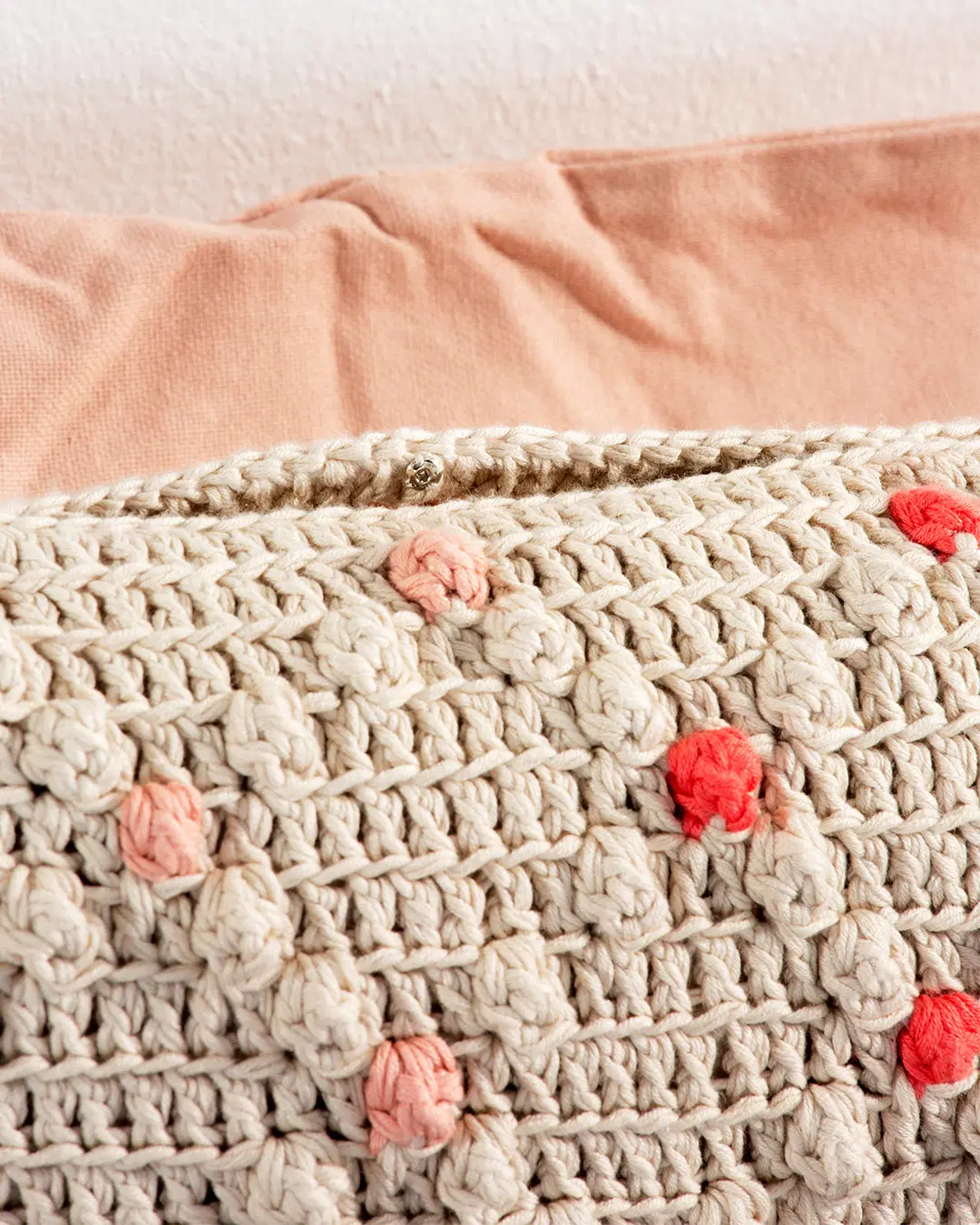 Lähikuva virkatun tyynyn reunasta, jossa on tyynyn sulkemiseen tarkoitettu neppari.