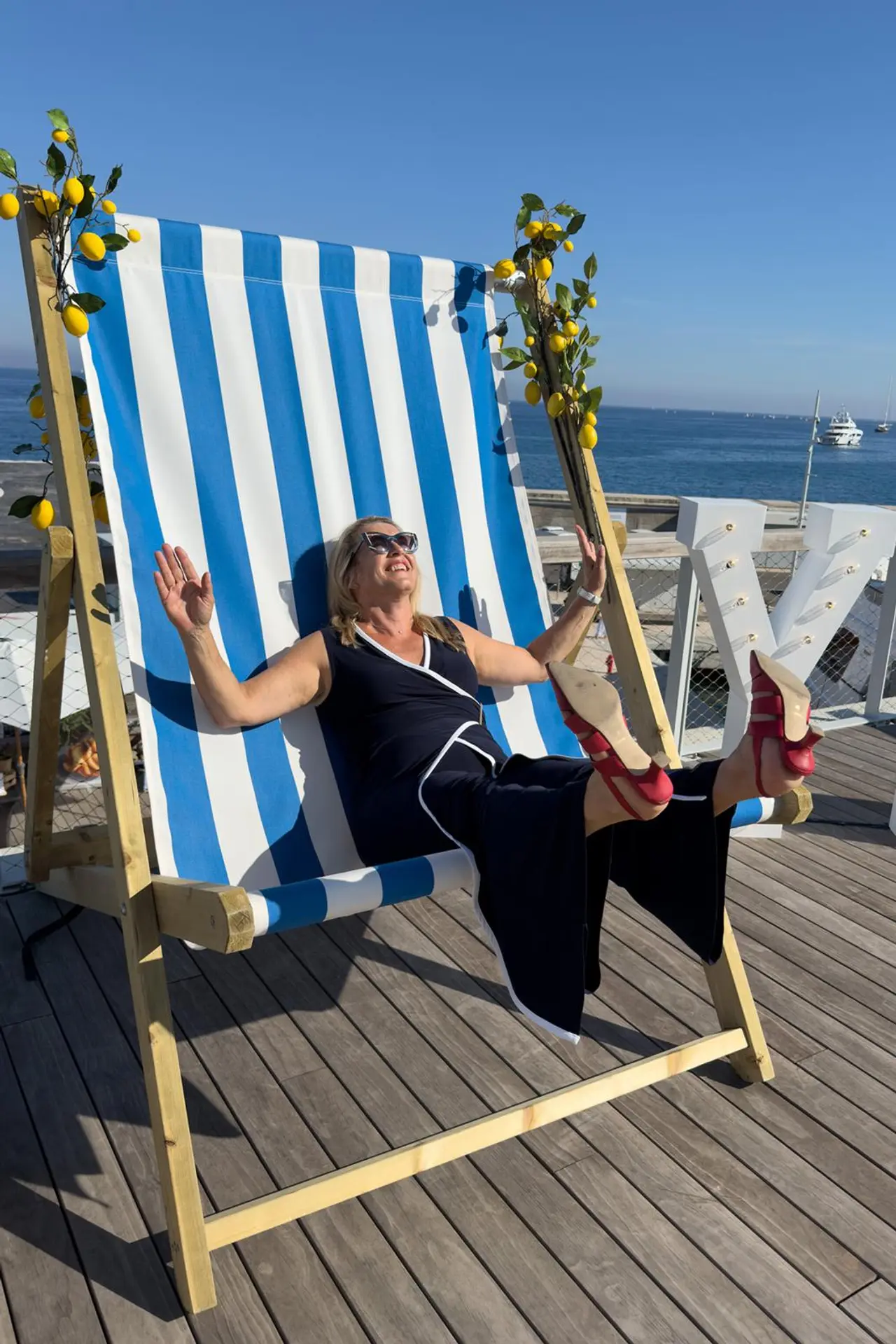 Titta Uoti-Väisänen istuu jalat ilmassa sinivalkoraidallisessa jättimäisessä rantatuolissa.