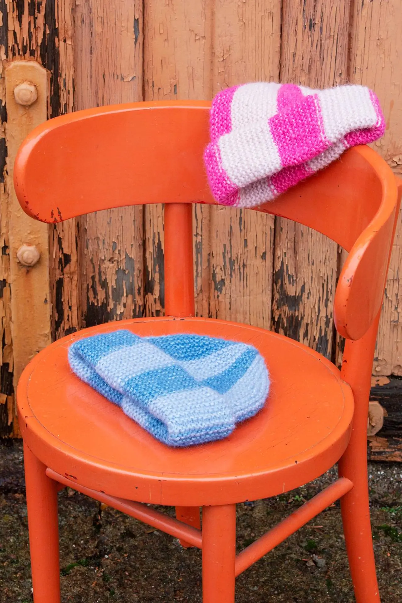 Kaksi raidallista pipoa oranssin tuolin päällä.