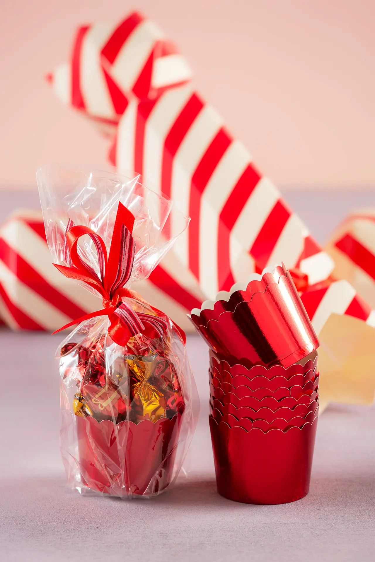 Kääreellisiä joulusuklaita punaisessa muffinssivuoassa sellofaanipussin sisällä.