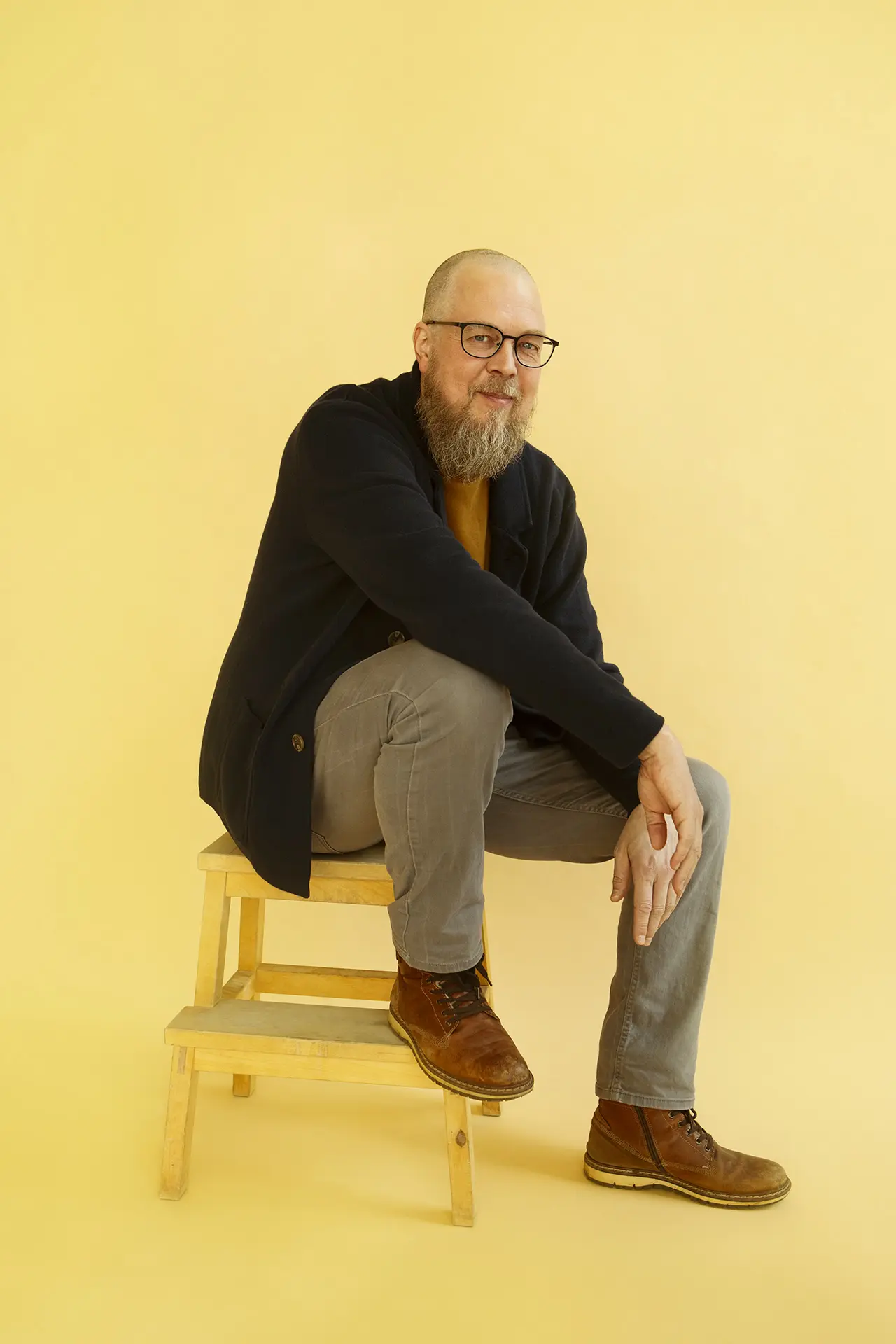 Tuomas Kyrö istuu puisella jakkaralla.