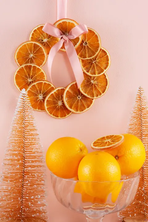 Kuivatuista appelsiiniviipaleista tehty kranssi seinälle ripustettuna.