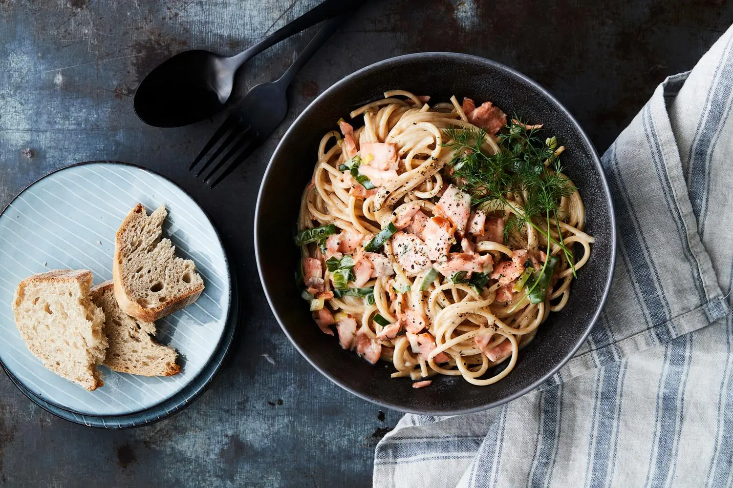 Oikealla kuvassa lautasellinen savulohipastaa ja vasemmalla lautanen, jossa revittyä vaaleaa leipää