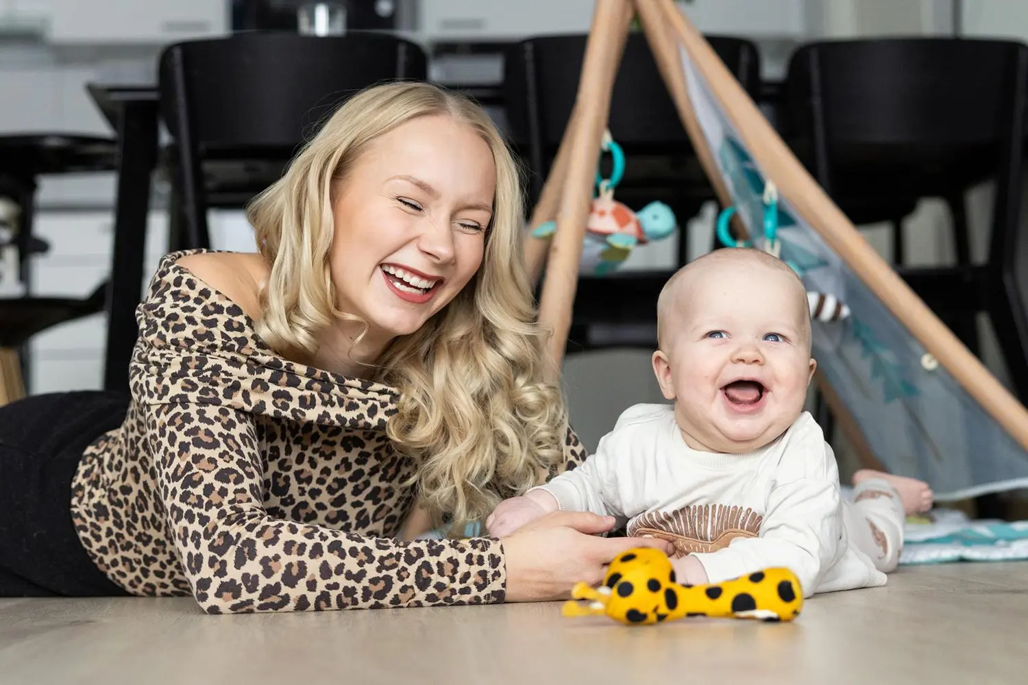 Äiti ja lapsi makaavat lattialla ja nauravat