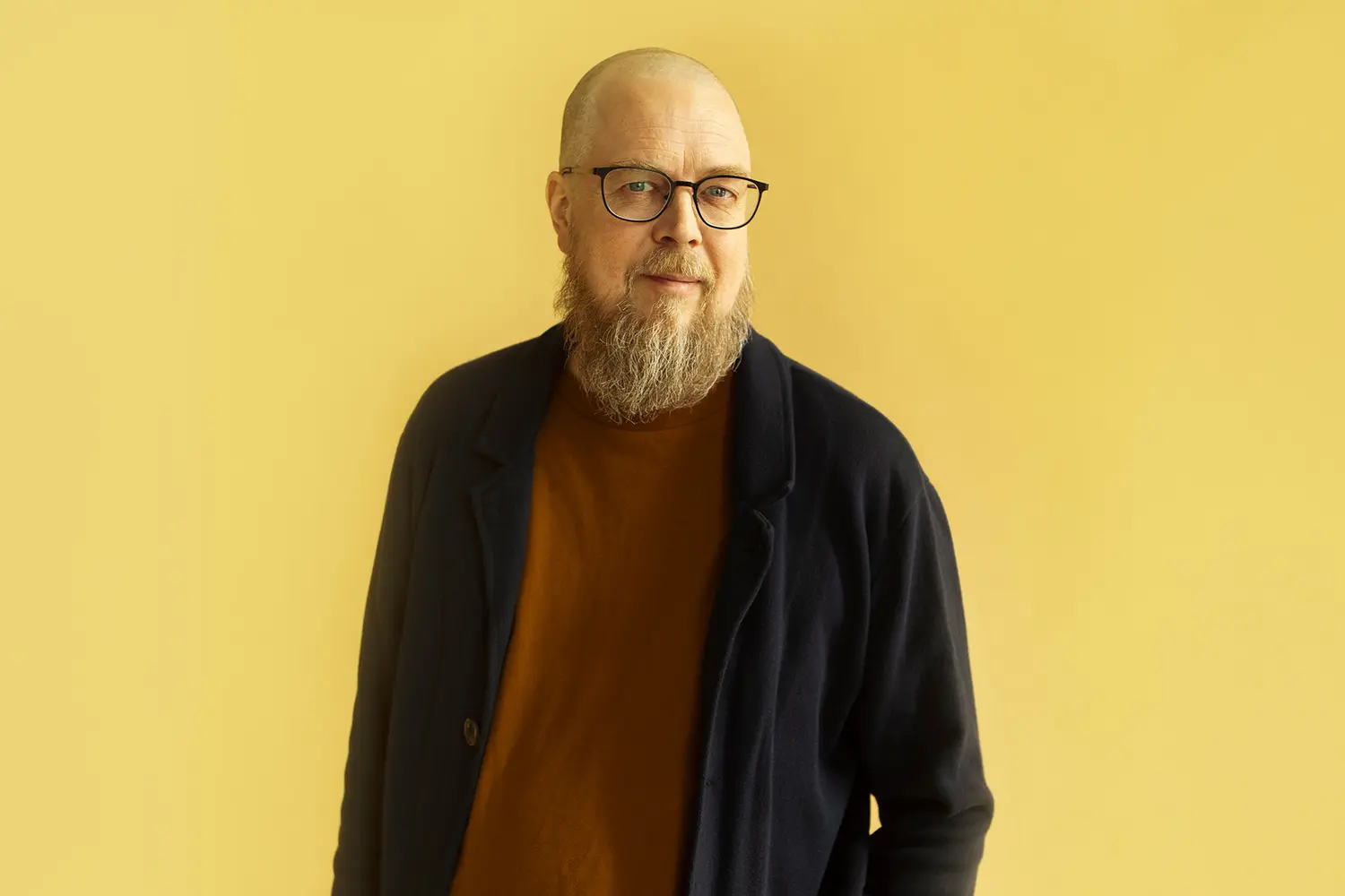 Tuomas Kyrö kuvattuna yksivärisellä taustalla.