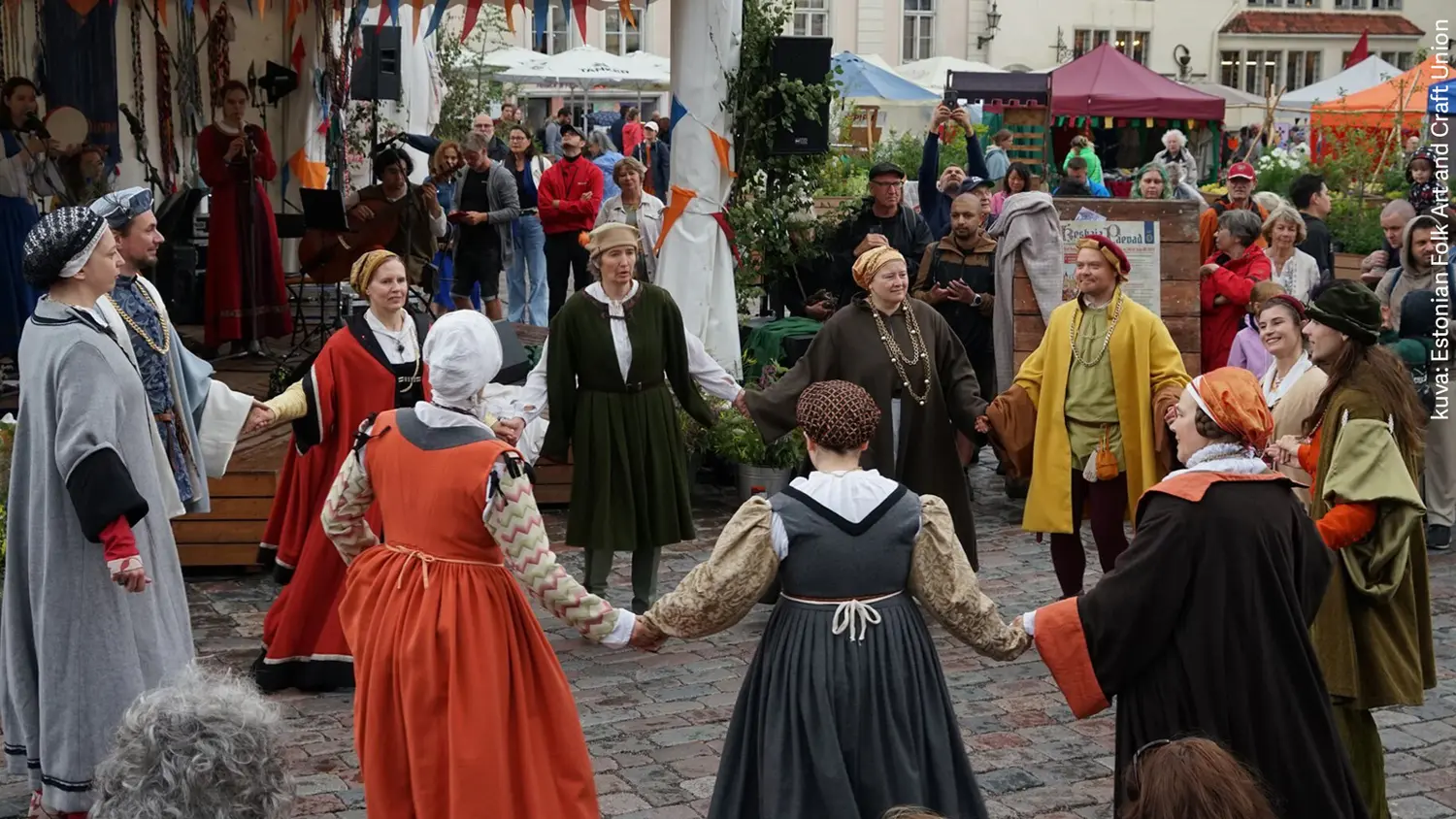Ihmisiä tanssii ringissä keskiaikaisissa asuissaan Tallinnan keskiaikapäivillä.