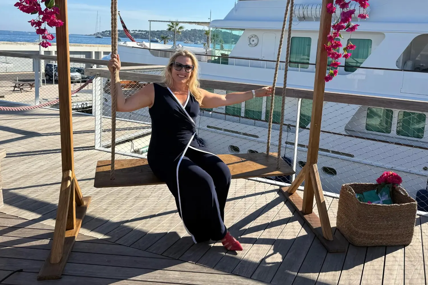 Titta Uoti-Väisänen istuu keinussa satamassa jahdin edustalla.