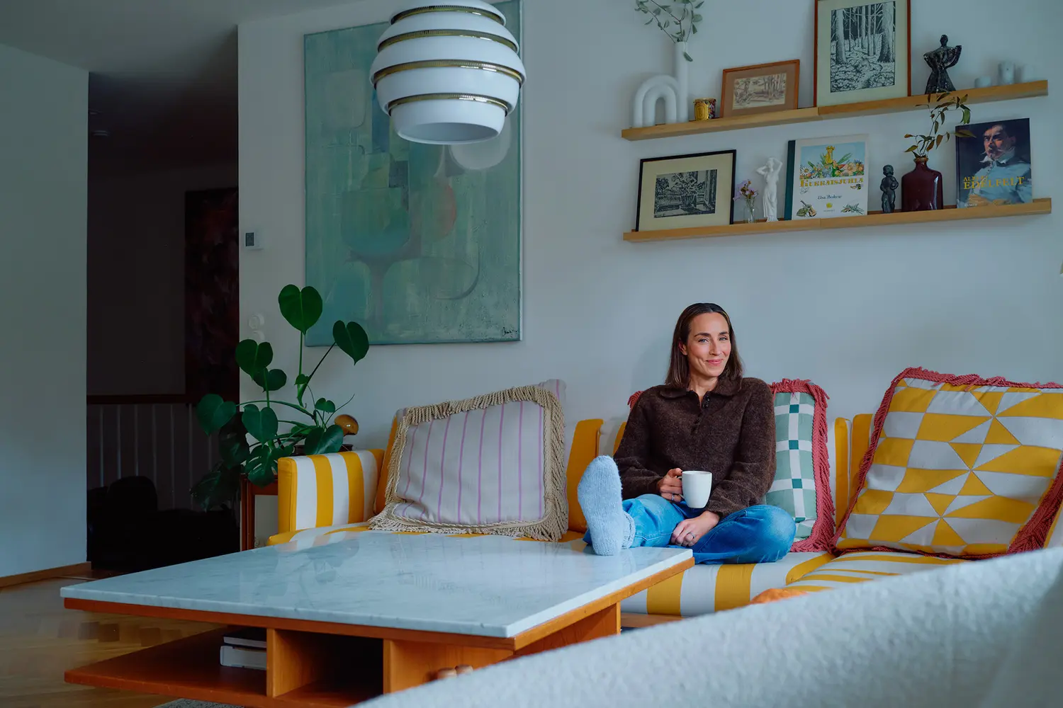 Anni Ihamäki istuu olohuoneensa suurella raidallisella sohvalla