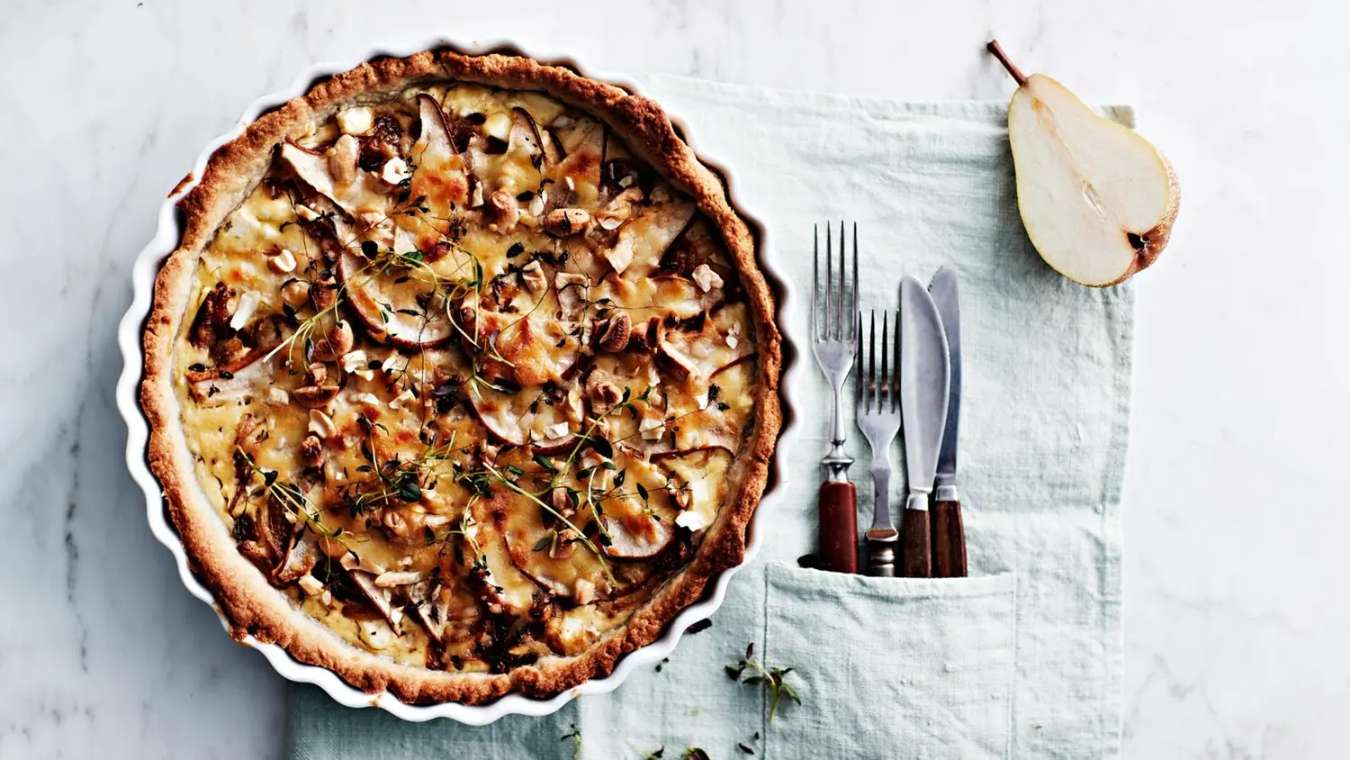 Kokonainen feta-päärynäpiirakka sekä haarukoita ja veitsiä.