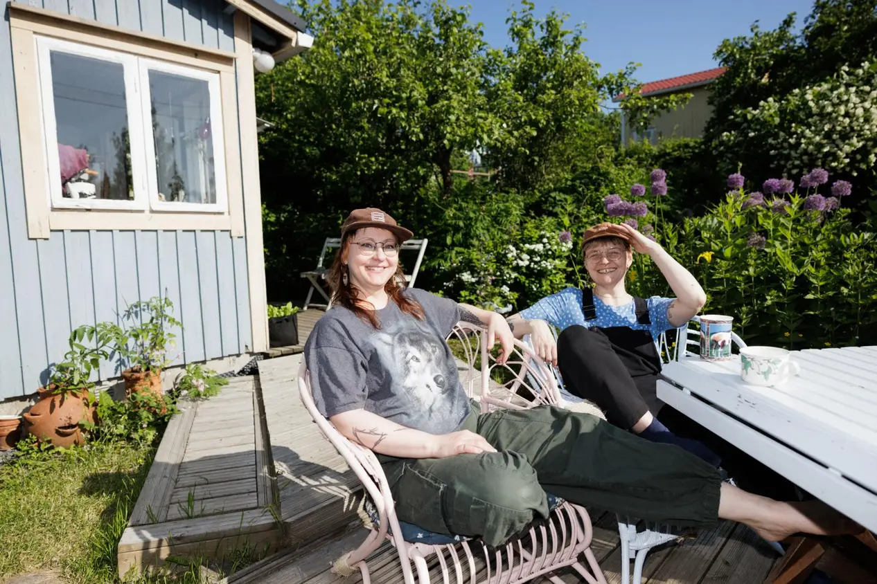 Eeva Naskali ja Sanni Seppä kuvattuna aurinkoisessa säässä siirtolapuutarhamökin pihalla.