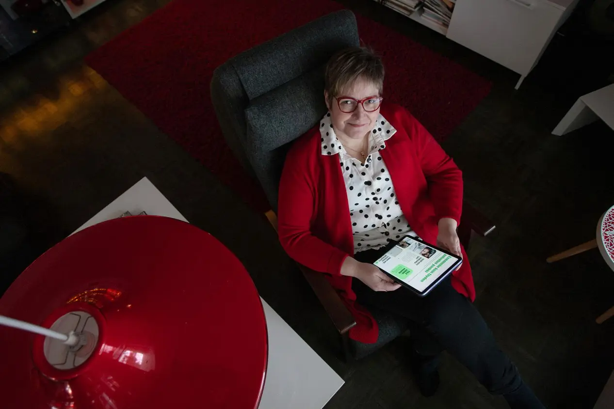 Henrika Mensah istuu nojatuolilla ja pitää kädessä tablettia