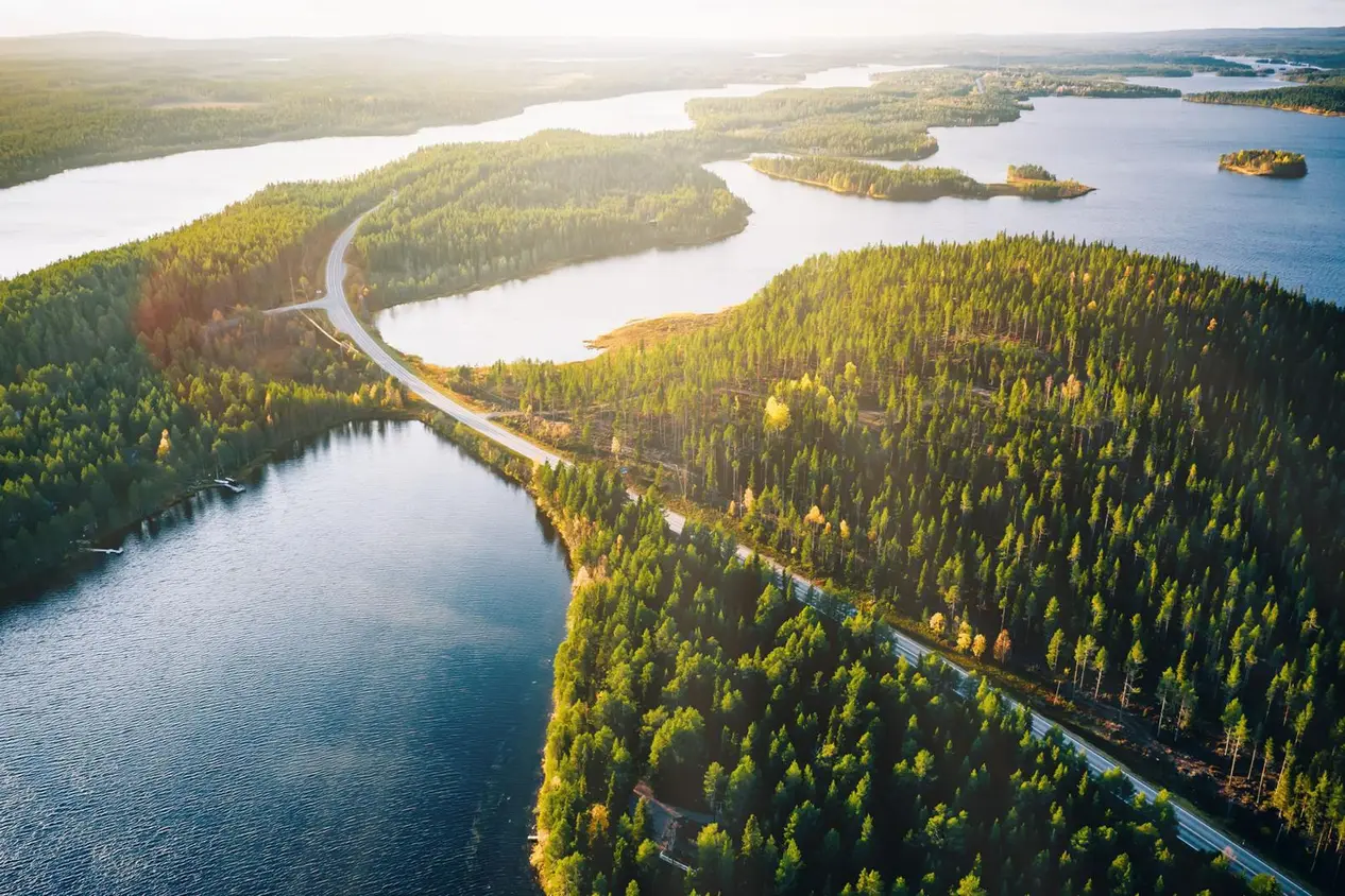 Ilmakuva, jossa näkyy metsien ja järvien keskellä mutkitteleva autotie.
