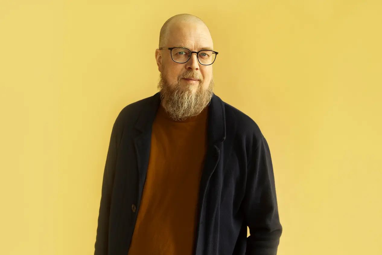 Tuomas Kyrö kuvattuna yksivärisellä taustalla.