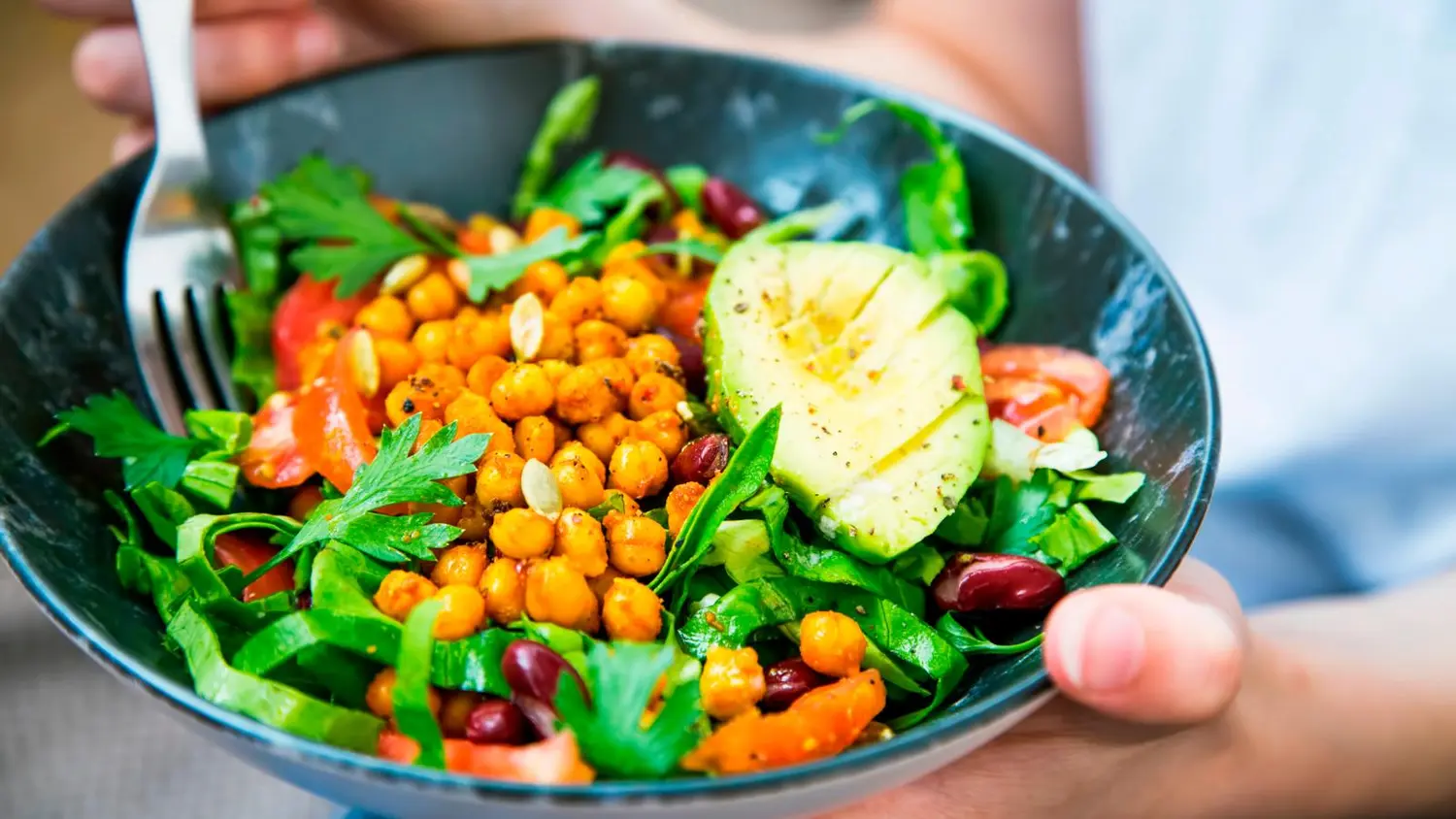 Kulhollinen ruokaisaa salaattia naisen käsissä