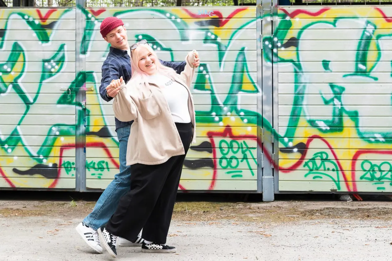 Opiskelijat Tom Sundberg ja Amanda Mäkinen tanssivat. Taustalla seinä, jossa on graffiteja.