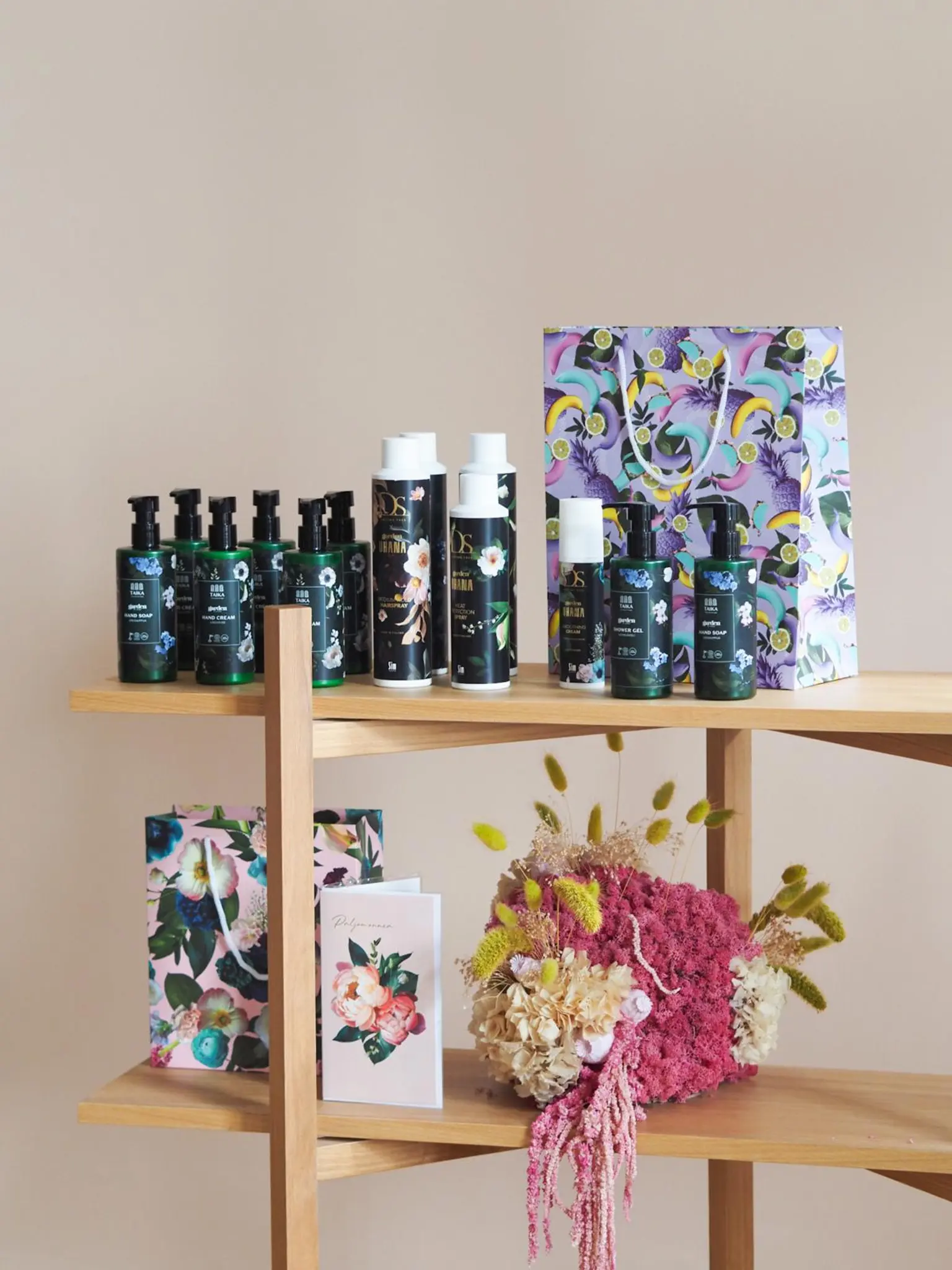 Garden by Uhana kosmetiikkapakkauksia, kaksi lahjakassia ja kortti puisessa hyllykössä