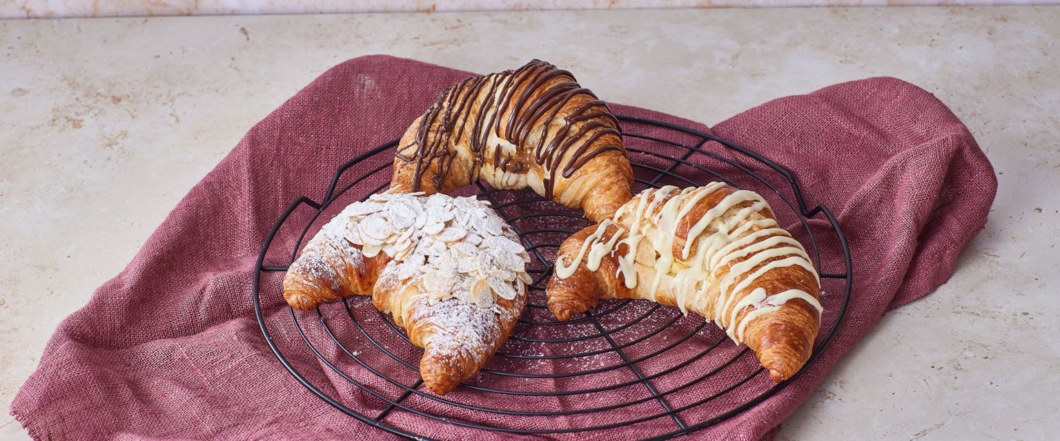 Tuoreita croissanteja jäähdytysritilällä punaisen liinan päällä