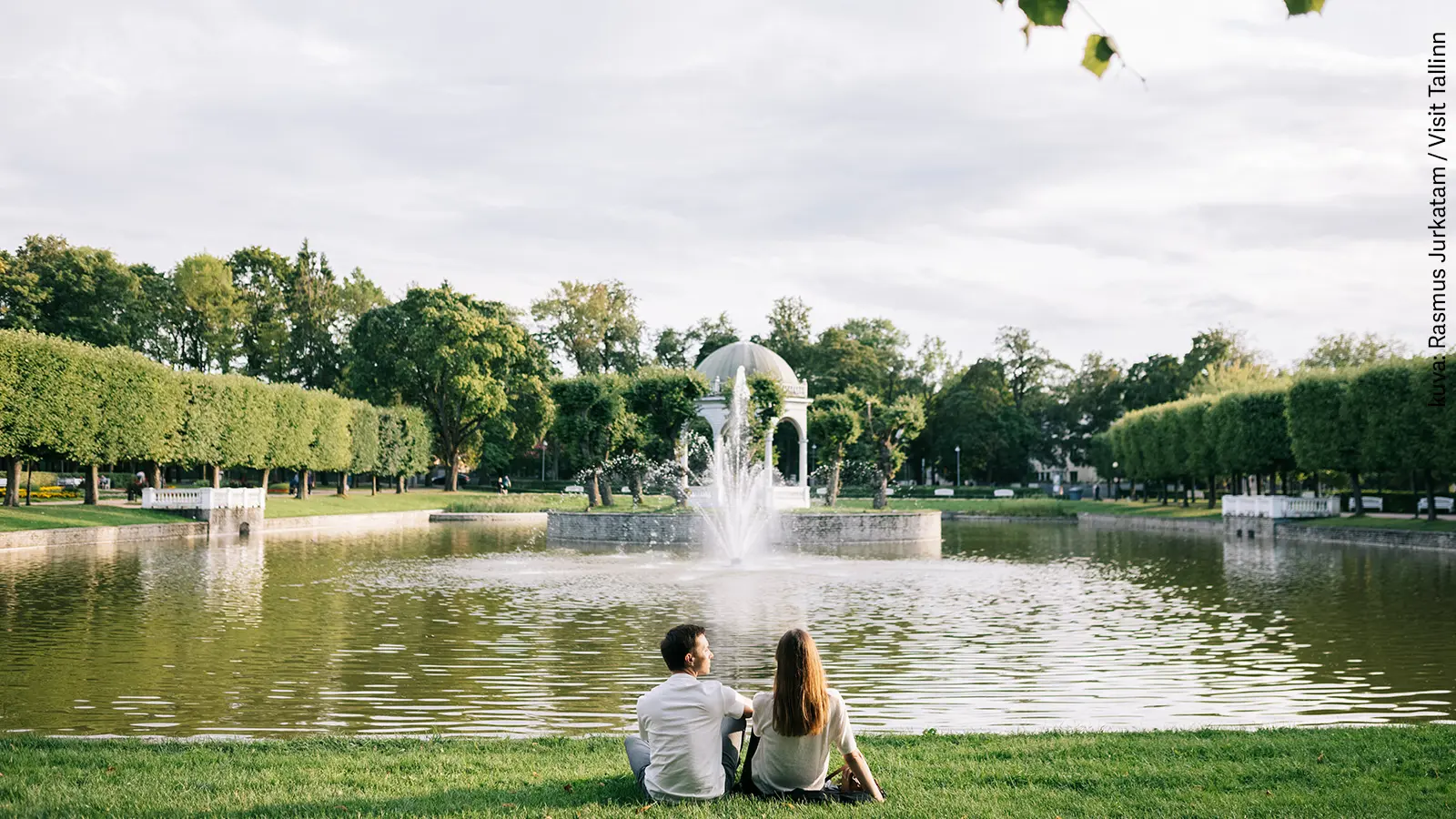 Pariskunta istuu selin kameraan Tallinnan kauneimmaksi kutsutussa Kadriorgin puistossa. 
