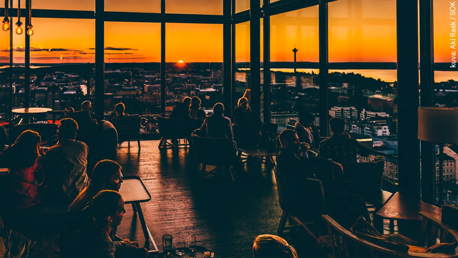 Sisäkuva ikkunoin ympäröidystä Moro Sky Barin kattobaarista auringon laskun aikaan.