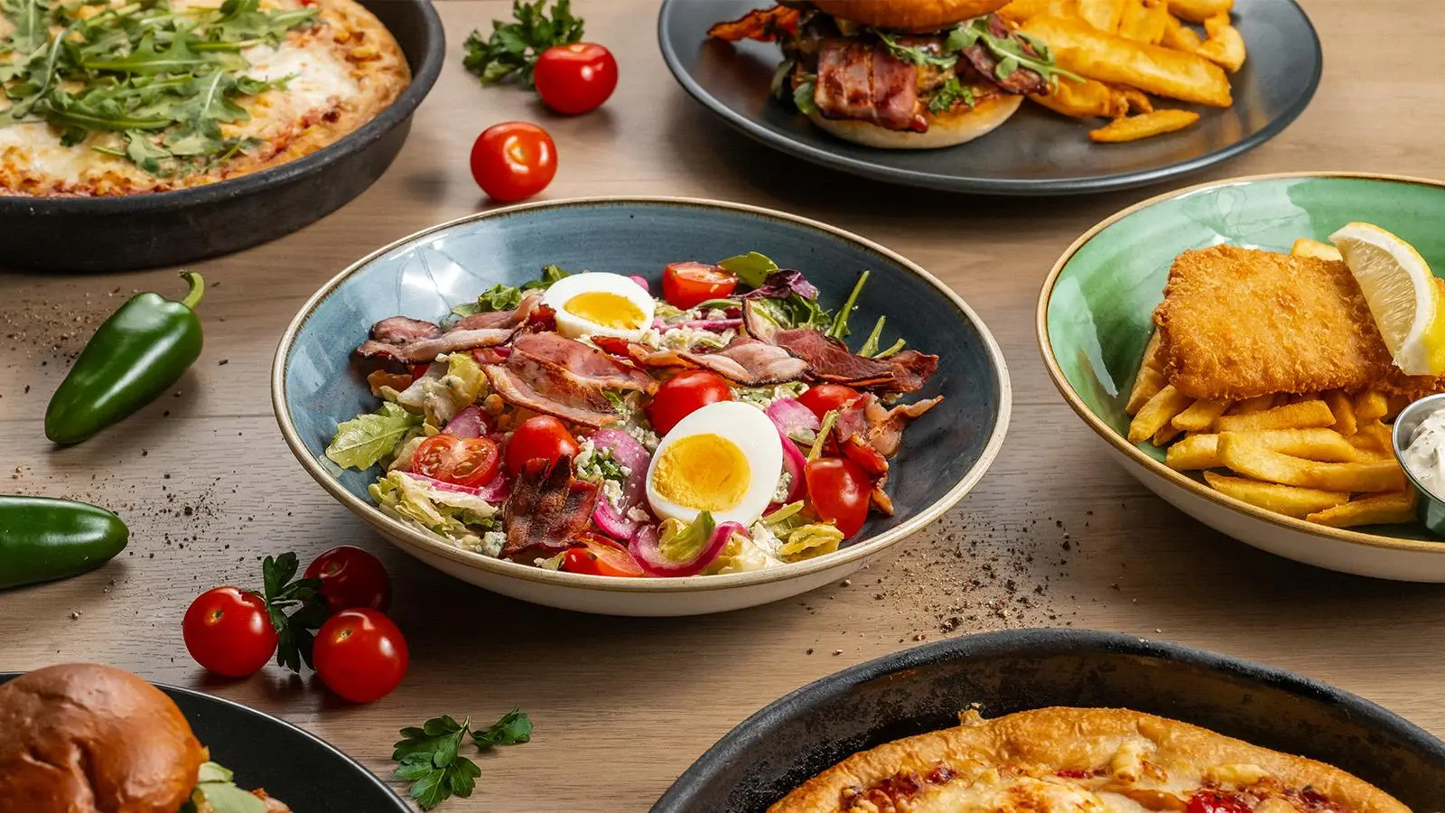 Ruoka-annoksia muun muassa kananmunaa ja pekonia sisältävä salaatti sekä rucolalla päällystetty pannupizza