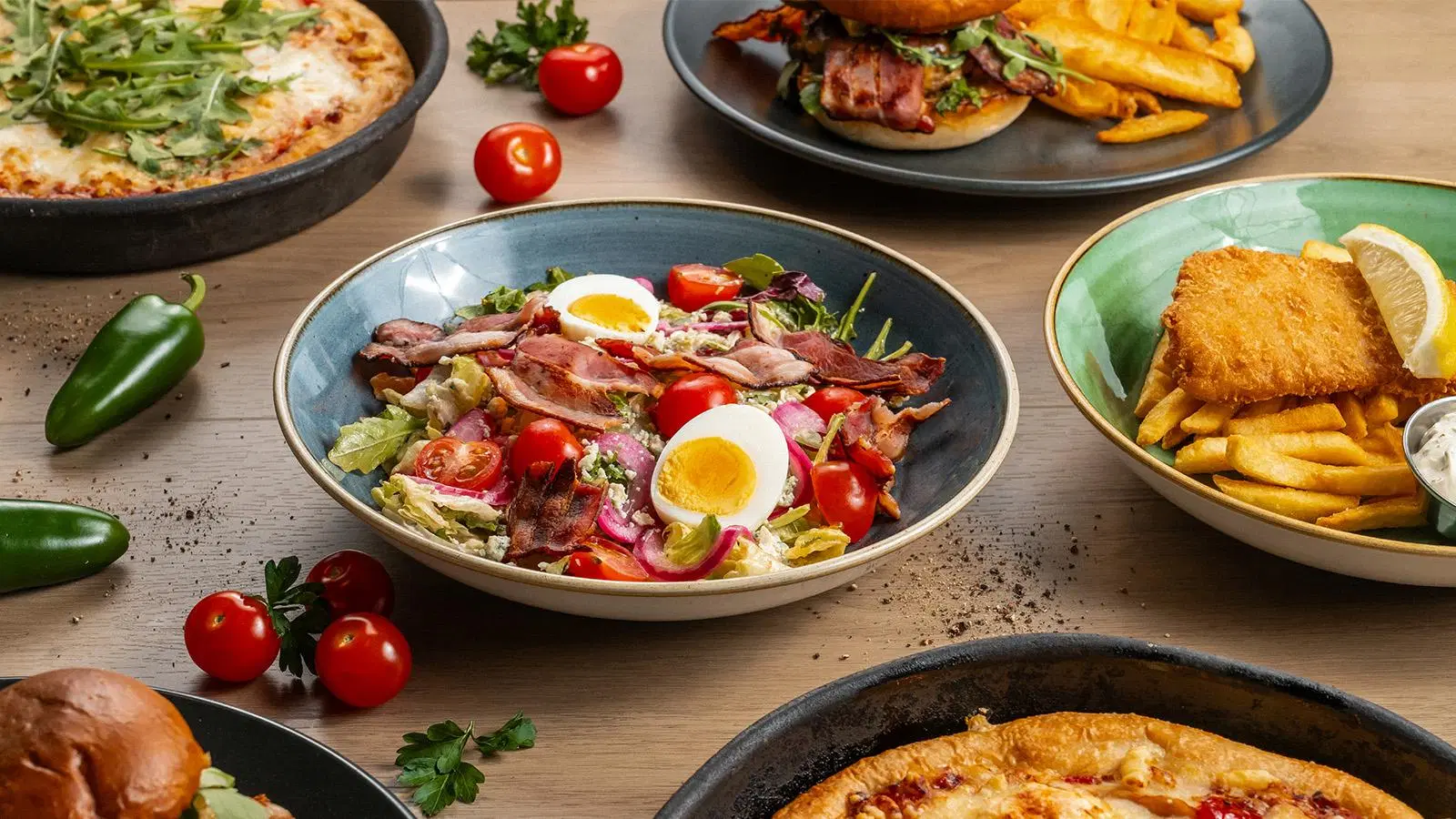 Ruoka-annoksia muun muassa kananmunaa ja pekonia sisältävä salaatti sekä rucolalla päällystetty pannupizza
