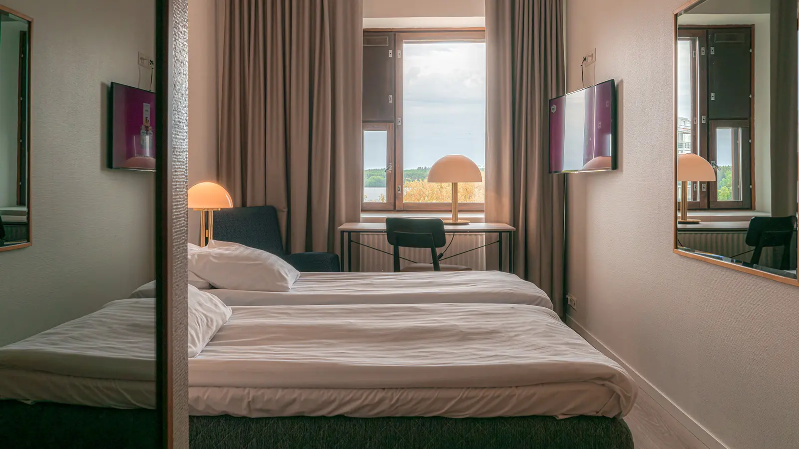 Hotelli Tottin vaaleansävyinen huone, jossa sänky ikkunan edustalla.