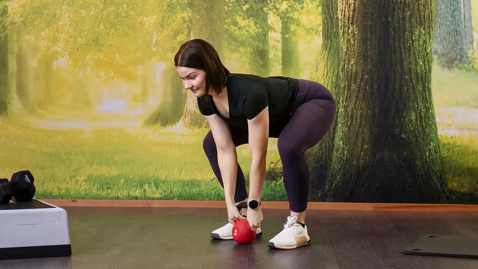 Nainen kumartuneena, kädessä kahvakuula.