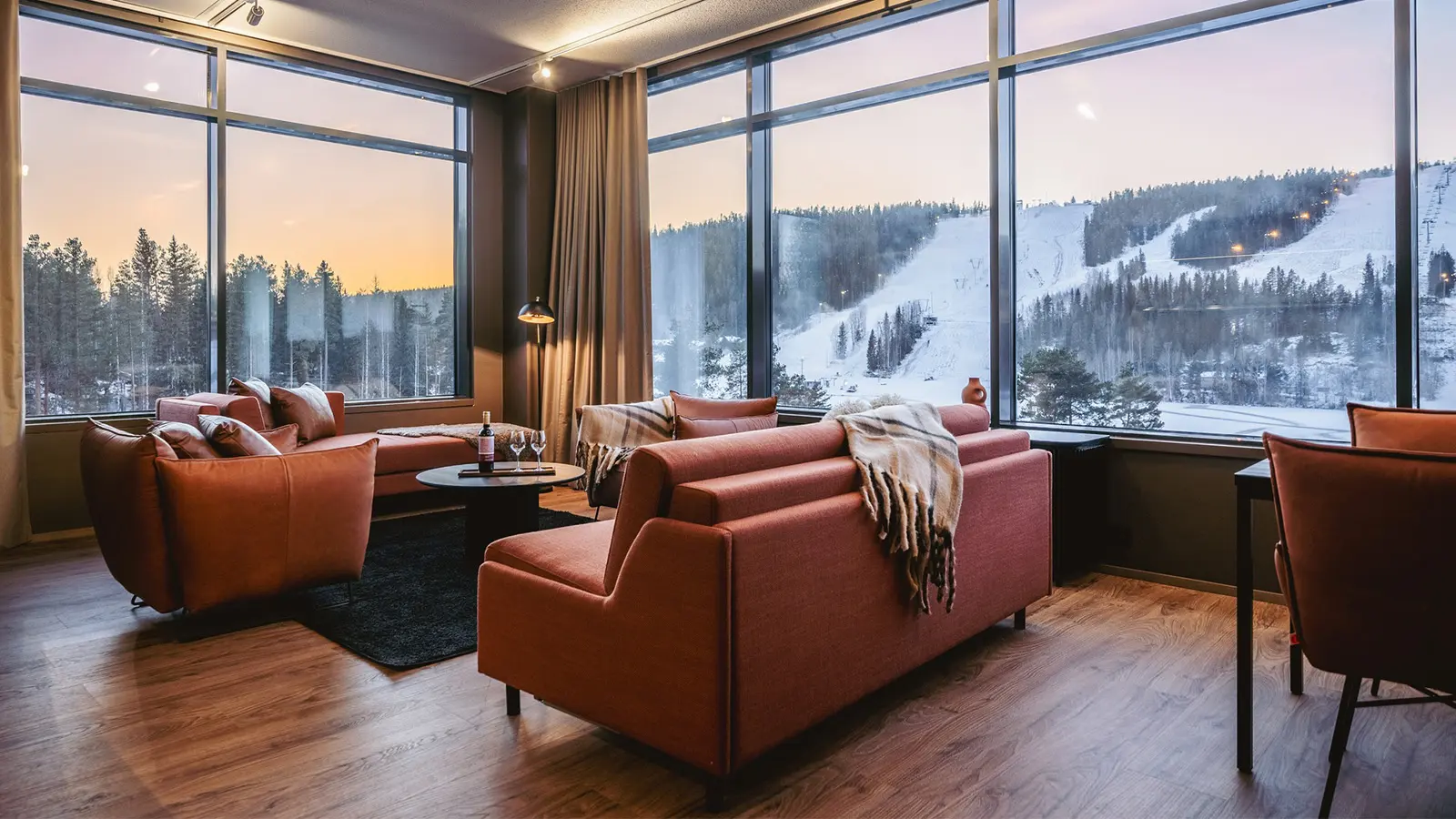 Break Sokos Hotel Tahkon sviitti jossa sohva, nojatuoleja, sohvapöytä ja isot ikkunat, joista näkyy luminen maisema