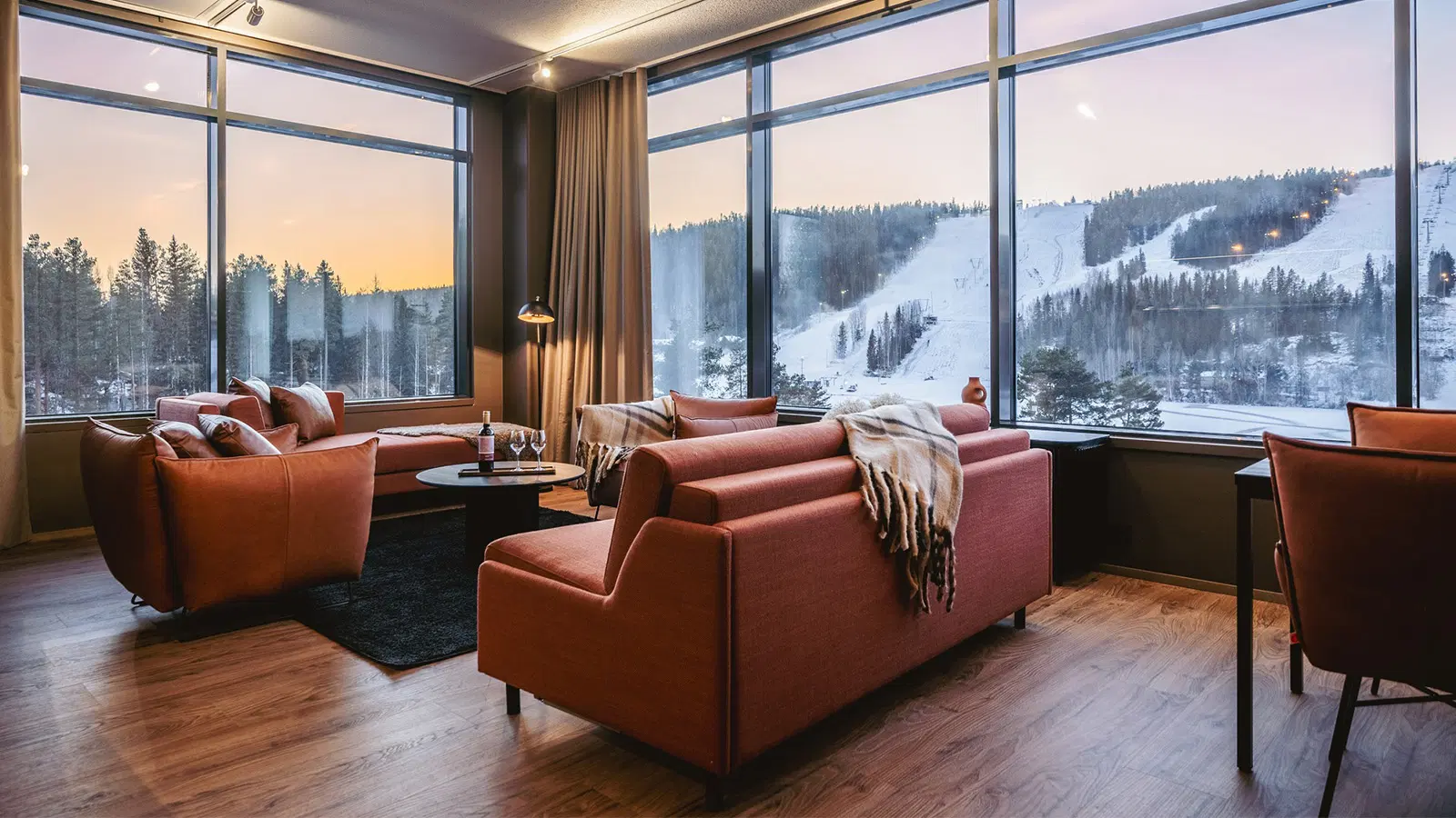 Break Sokos Hotel Tahkon sviitti jossa sohva, nojatuoleja, sohvapöytä ja isot ikkunat, joista näkyy luminen maisema