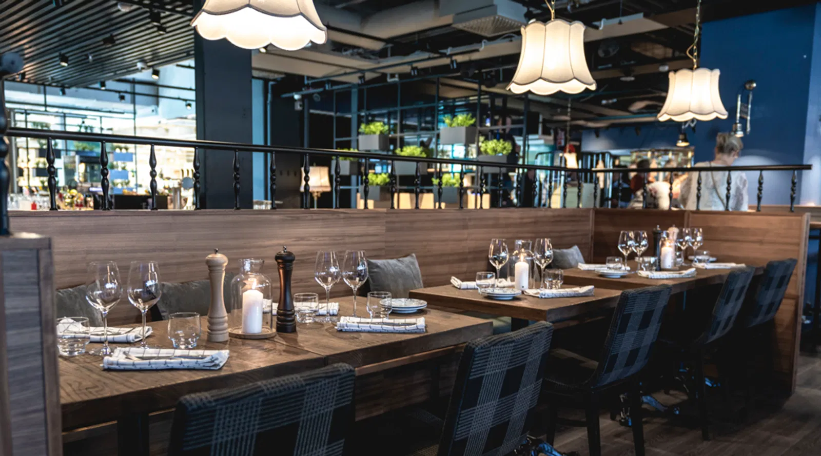 Trattoria Wiklundin sali: pitkä sohvaosasto, katetut puupöydät ja rivi riippuvalaisimia