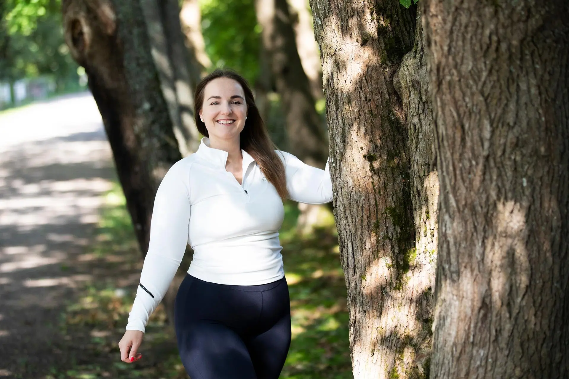 Veronica Hirvilammi ulkona, nojaa kädellä puuhun.