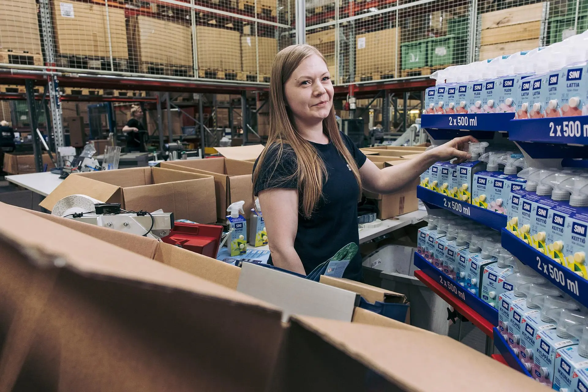 Kati Koskinen pakkaa Sinituote-suihkepulloja.