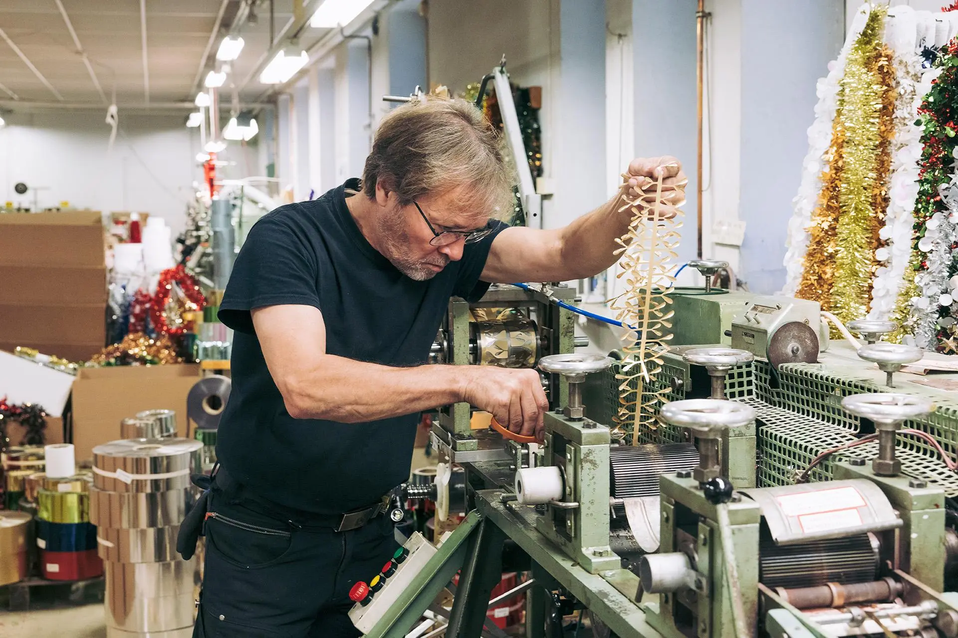 Pasi Hietanen huoltaa tehdaskonetta, joka tekee koristeköynnöstä