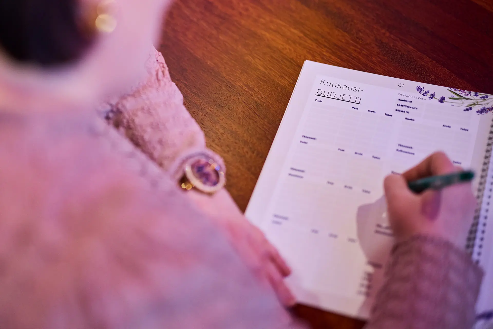 Sanna Latvala täyttää budjettikirjaa kynä kädessä.