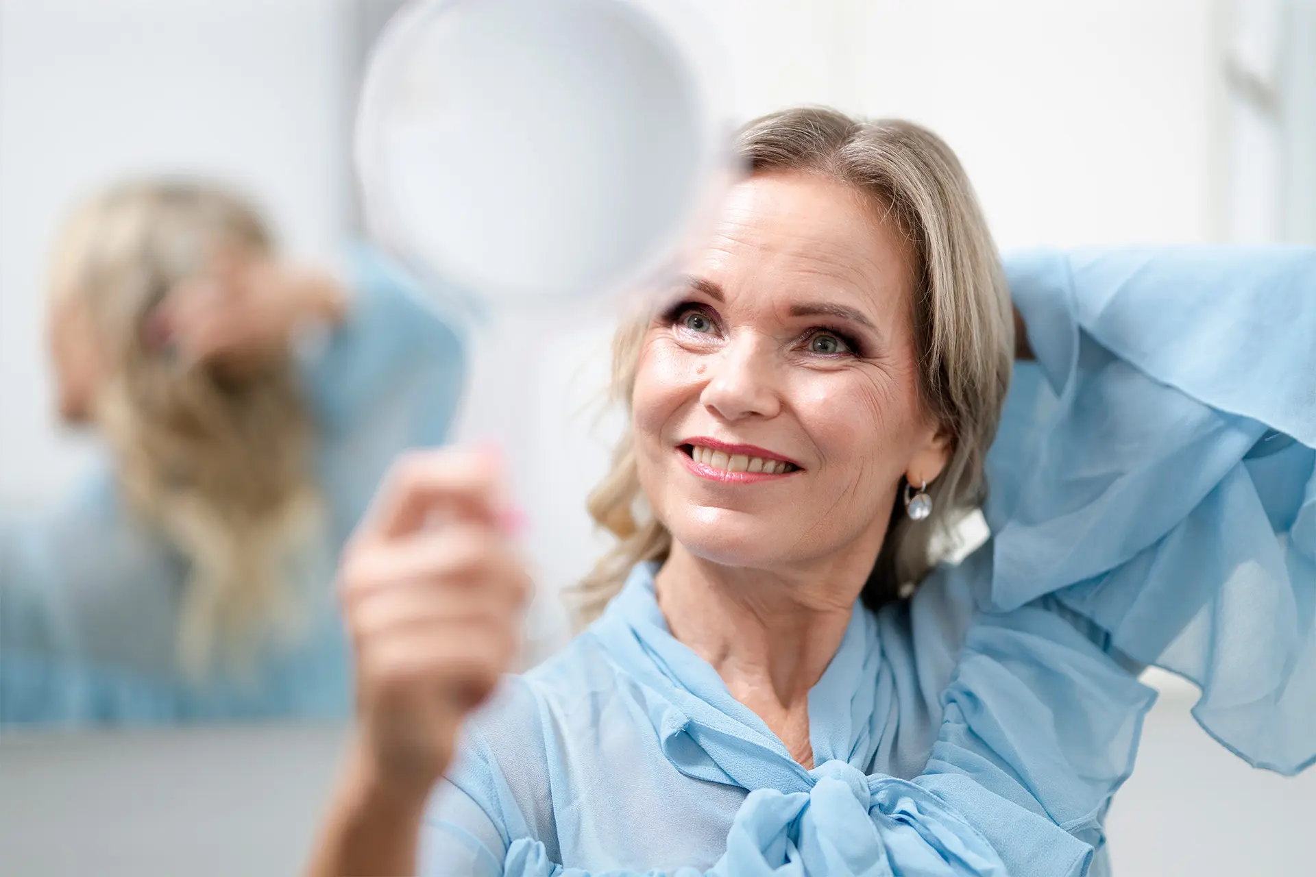 Satu Rusanen katsoo itseään käsipeilistä.