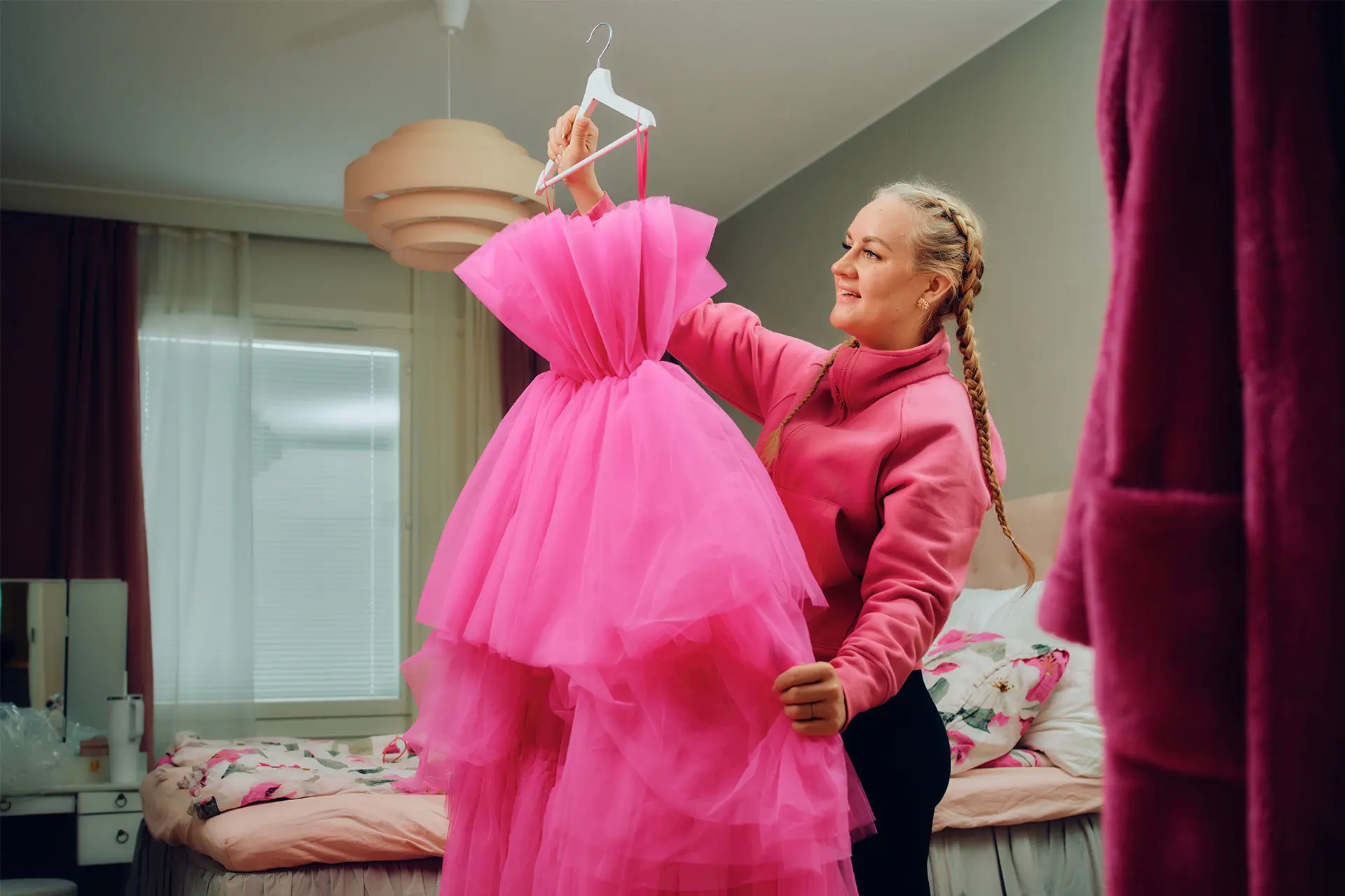 Auri Kananen pitää kädessään pinkkiä tyllimekkoa, taustalla makuuhuone.
