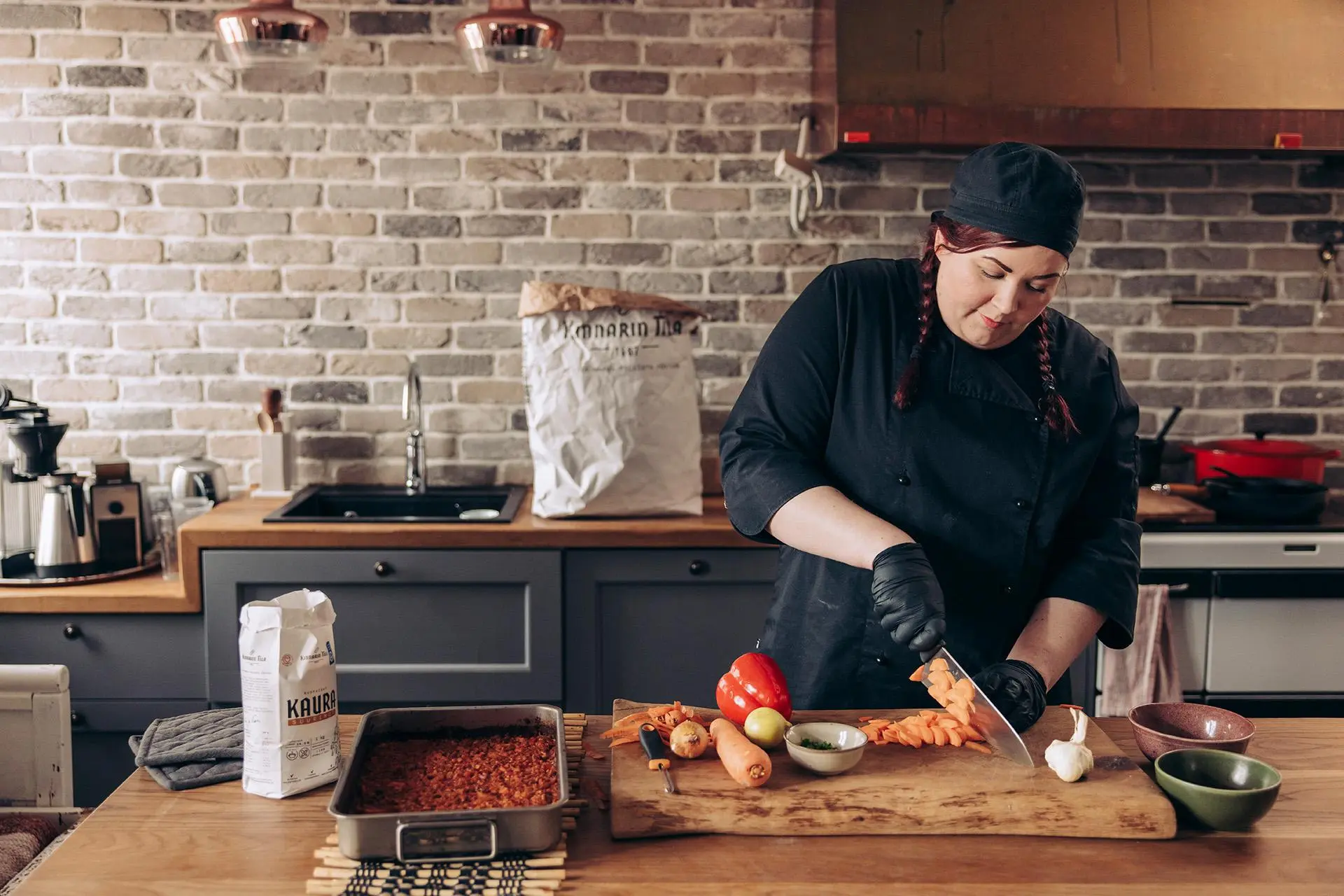 Jenni Turkki pilkkoo kasviksia suurella leikkuulaudalla.