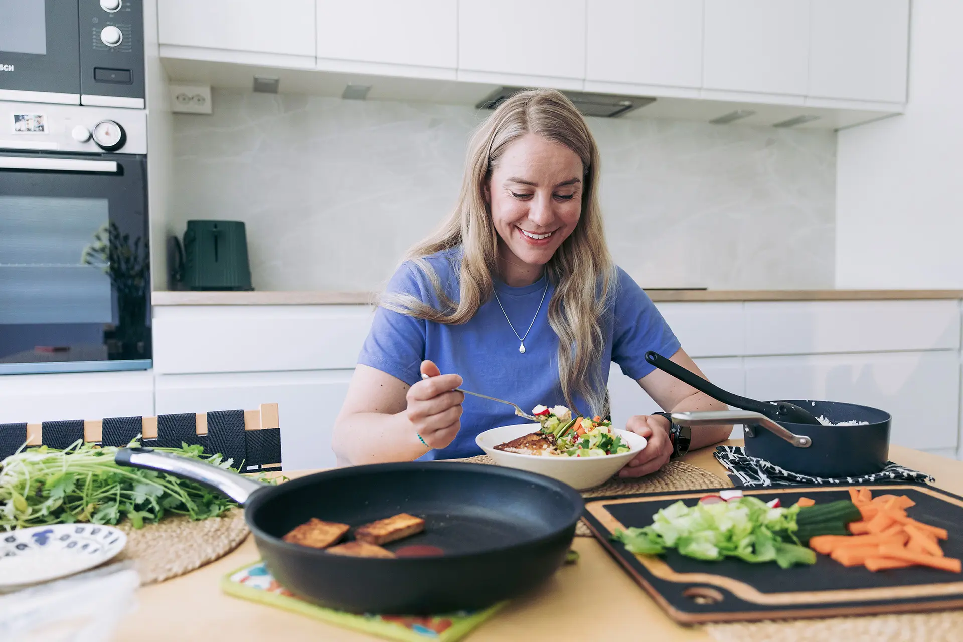 Anni Penttilä syö salaattia keittiön pöydän ääressä.