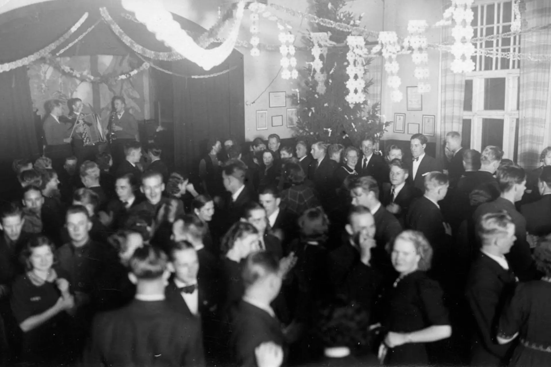 Historiakuvassa suuri ihmisjoukko juhlimassa salissa