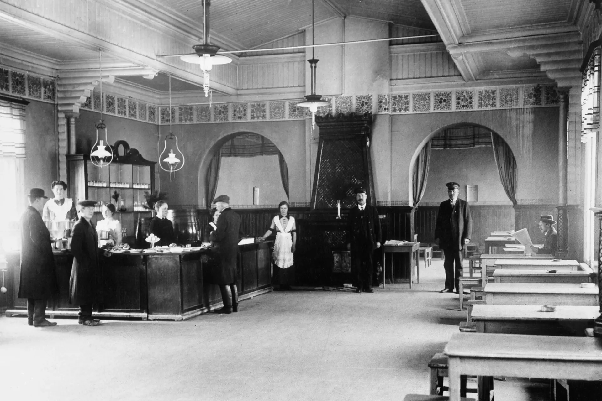 Historiakuvassa ihmisistä ravintolassa, jossa on tiski ja pöytiä