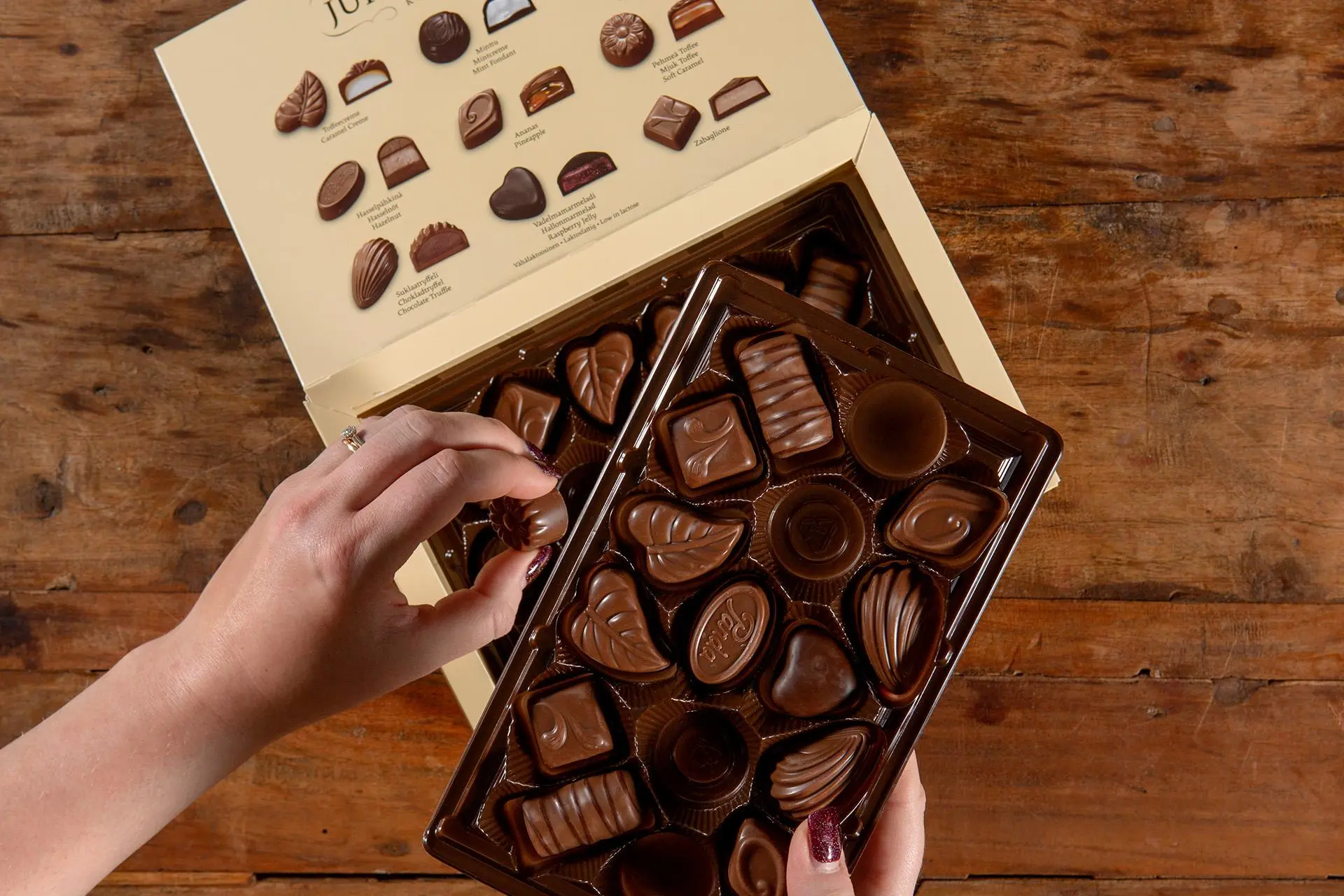 Käsi ottaa suklaakonvehtia rasian alemmasta kerroksesta.