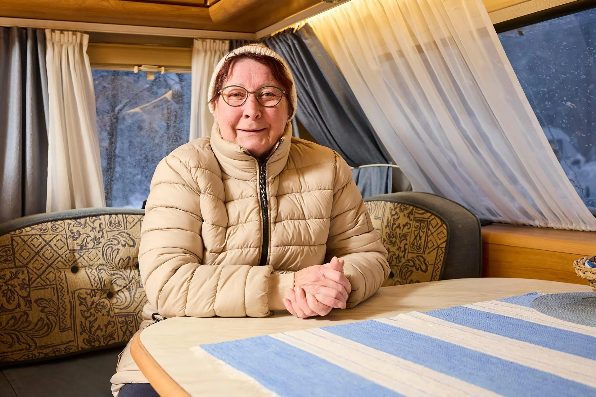 Rauni Myllykangas istuu asuntovaunun sohvalla toppatakki päällä