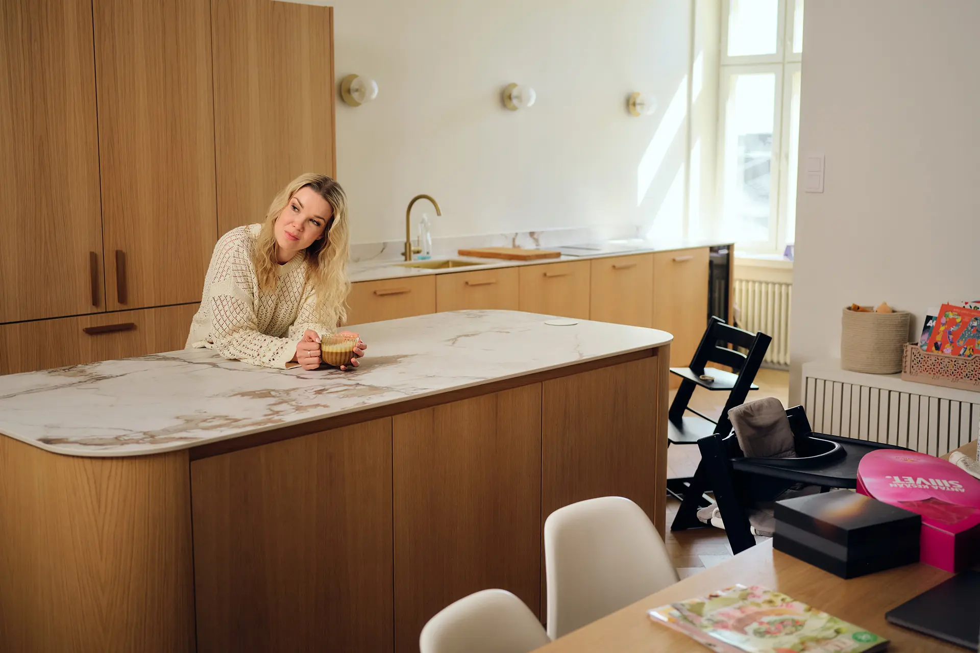 Tuija Pehkonen nojaa suureen saarekkeeseen modernisti sisustetussa keittiössä.