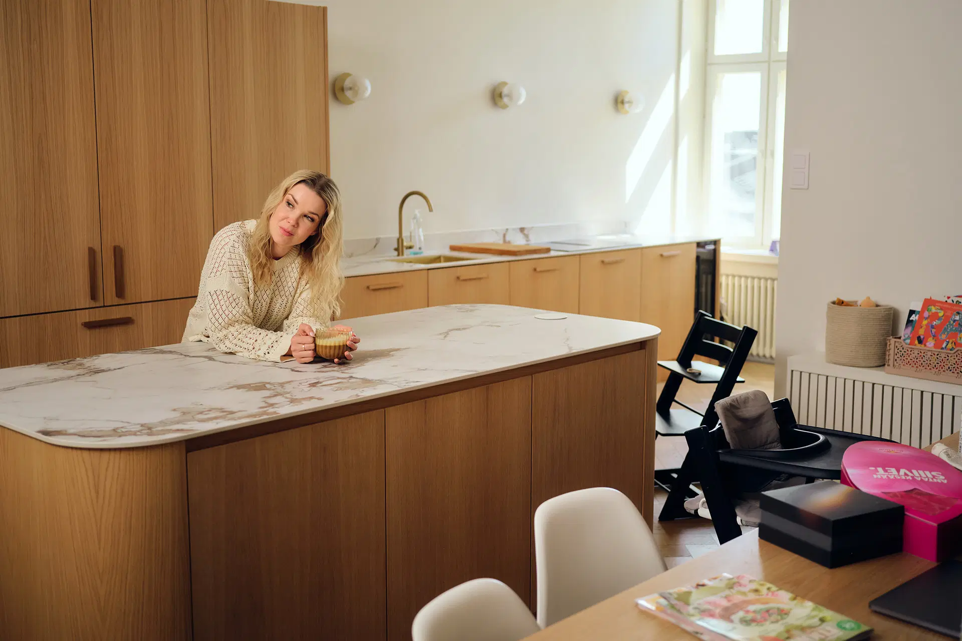 Tuija Pehkonen nojaa suureen saarekkeeseen modernisti sisustetussa keittiössä.
