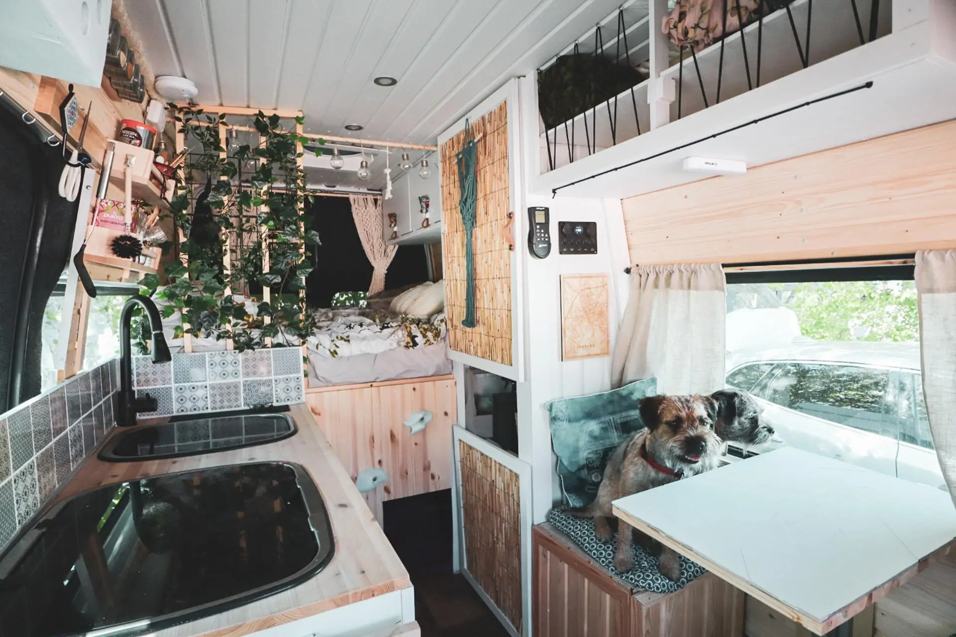 Matkailuauton keittiö, jossa on pieni liesitaso, tiskiallas ja kahden henkilön istuttava pöytä.